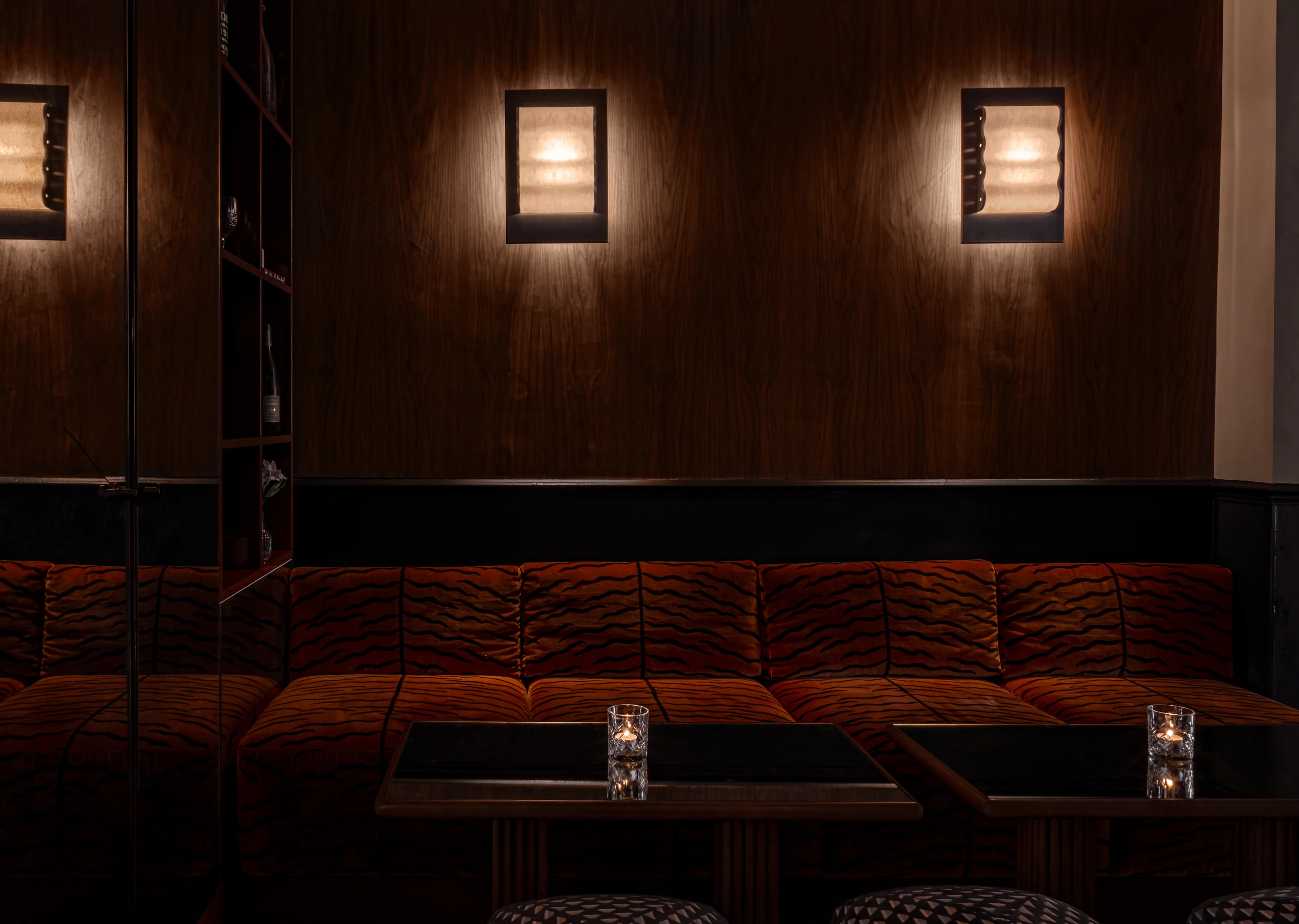 Stylish interior design featuring dark wood paneling, tiger-print furniture, and candlelit tables at Hôtel Le Garage, Biarritz.