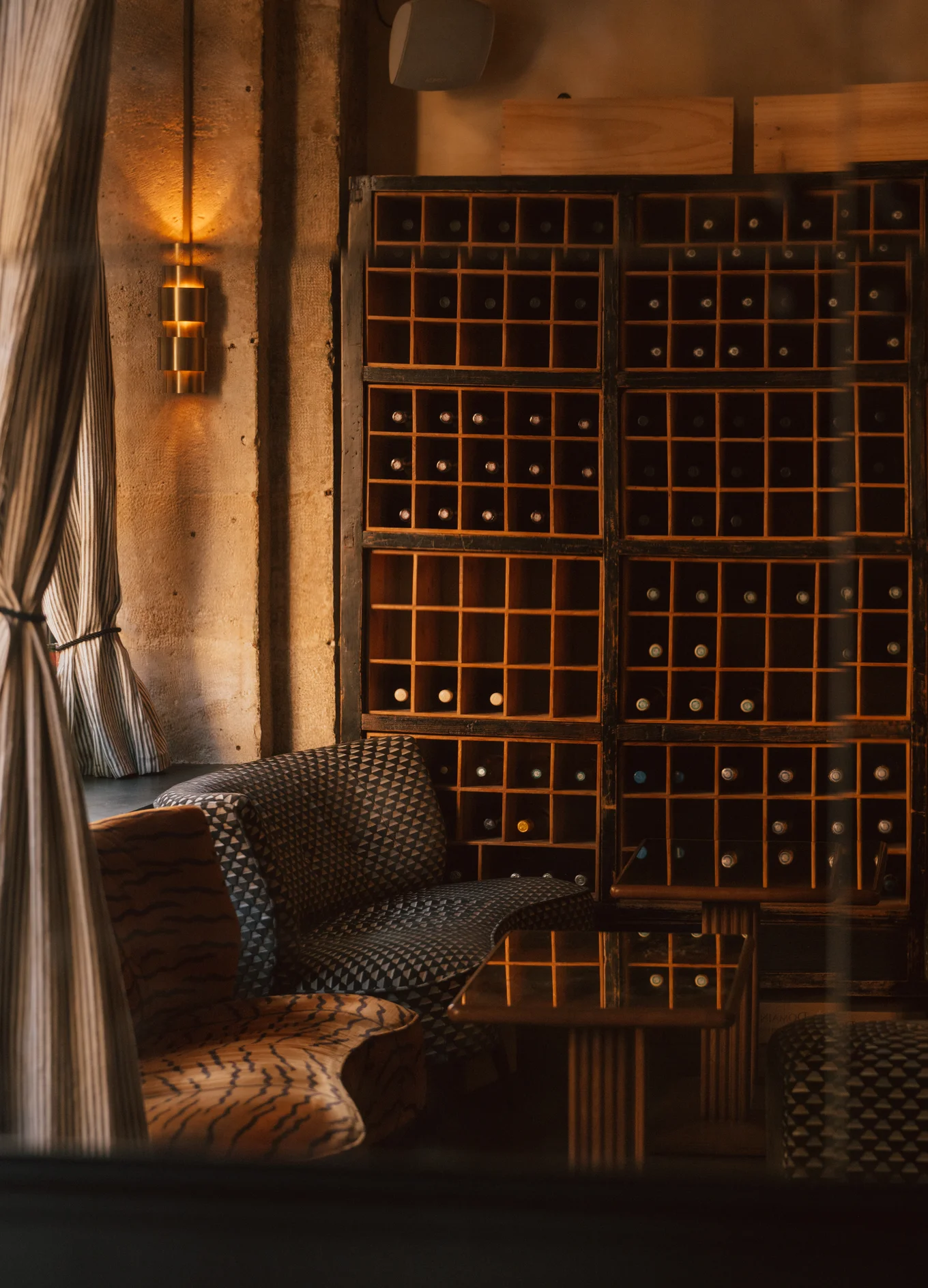 Interior view of the wine cellar and lounge area with patterned armchairs at Hôtel Le Garage, Biarritz.