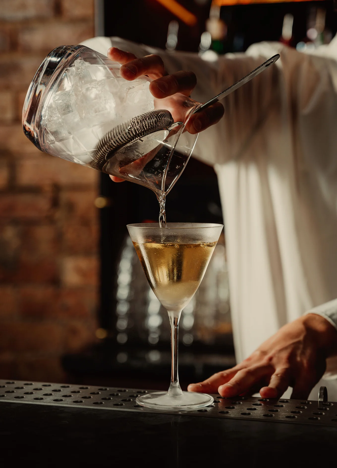 Professional bartender pouring a signature cocktail into a chilled glass, Experimental Group.