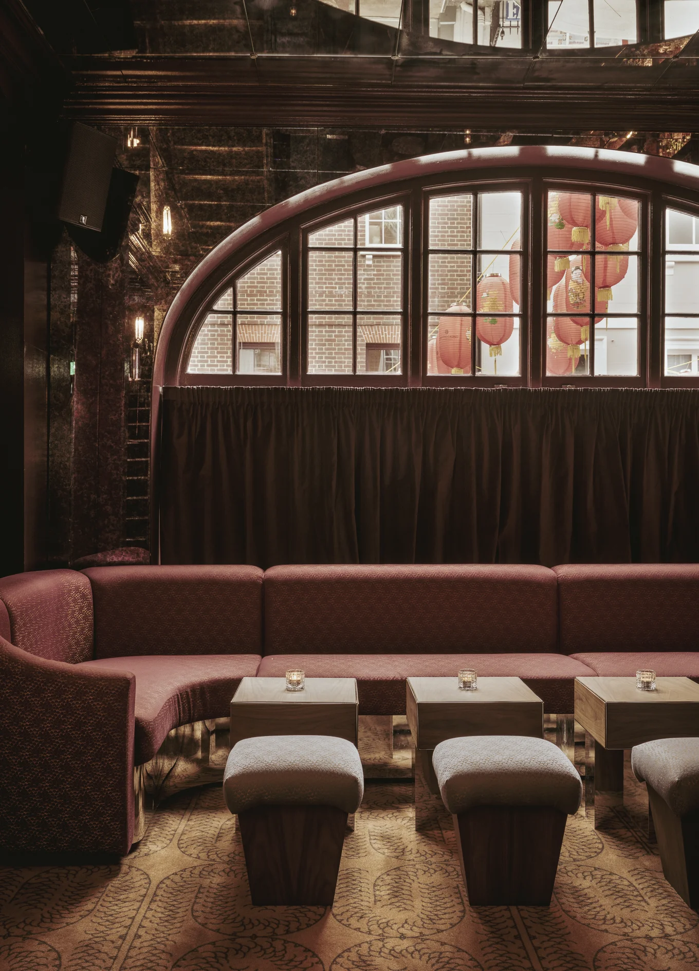 Stylish lounge area with sofas and red lanterns visible through the window, Experimental Group interior design.