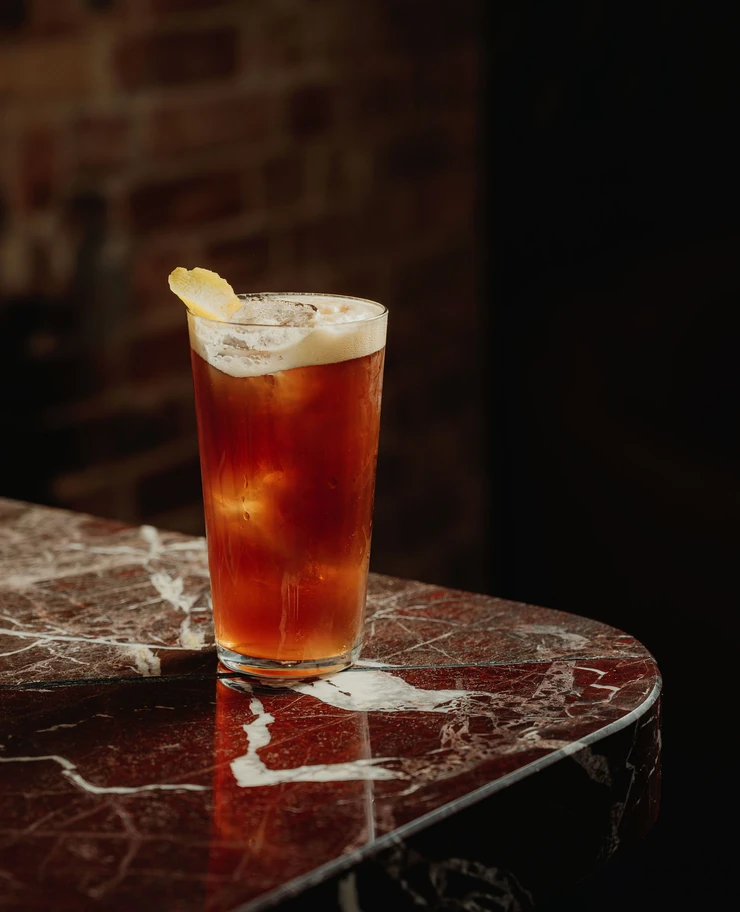 Close-up of a refreshing cocktail on a dark marble bar counter, Experimental Group bar ambiance.