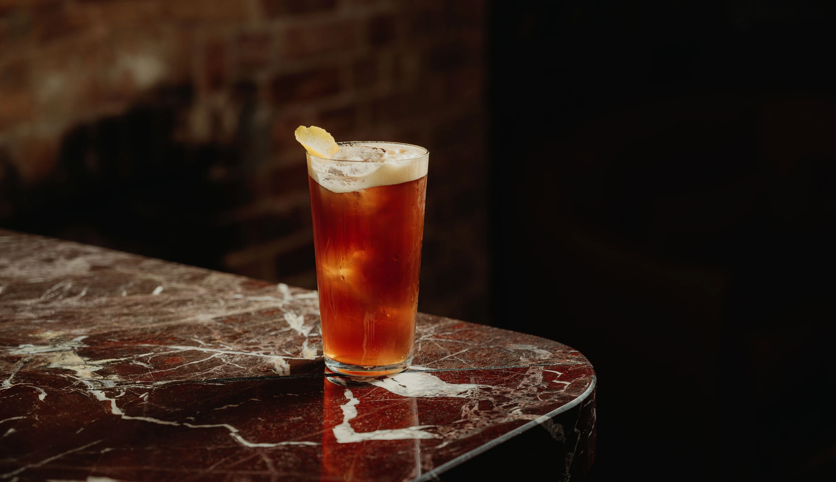 Signature cocktail in a highball glass with citrus garnish, served at an Experimental Group bar.
