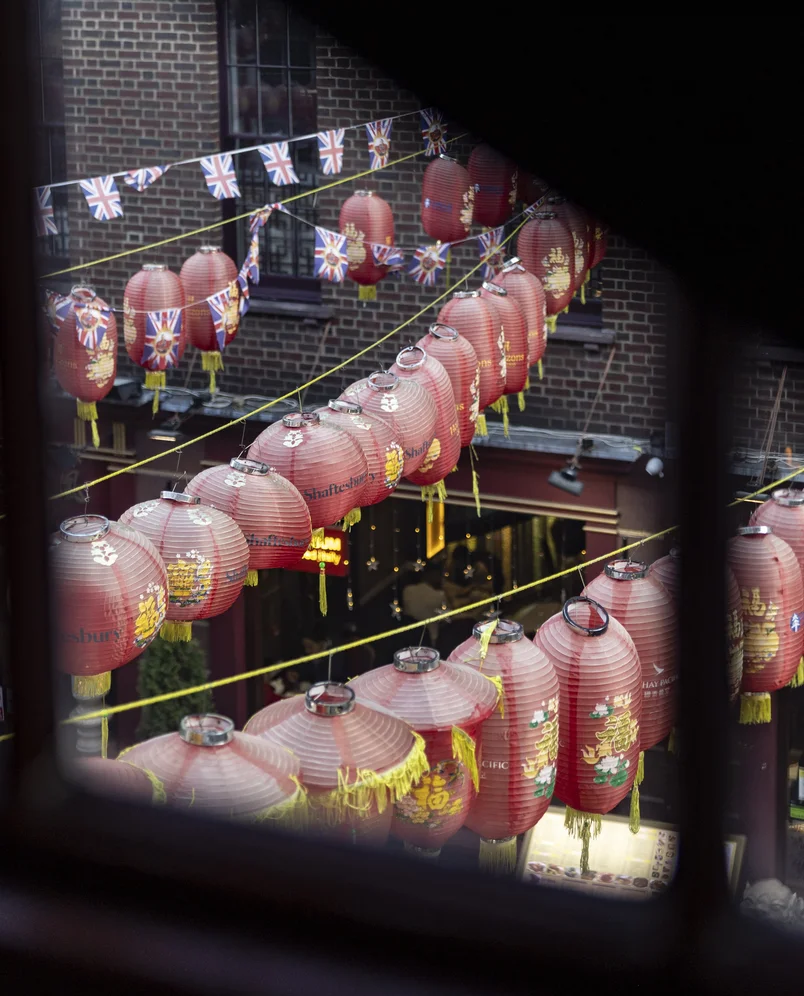 View from a window of a street decorated with red lanterns and British flags, Chinatown, London.