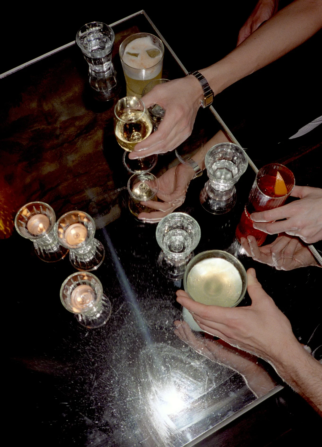 Friends enjoying craft cocktails at a reflective table in an intimate Experimental Group bar setting.