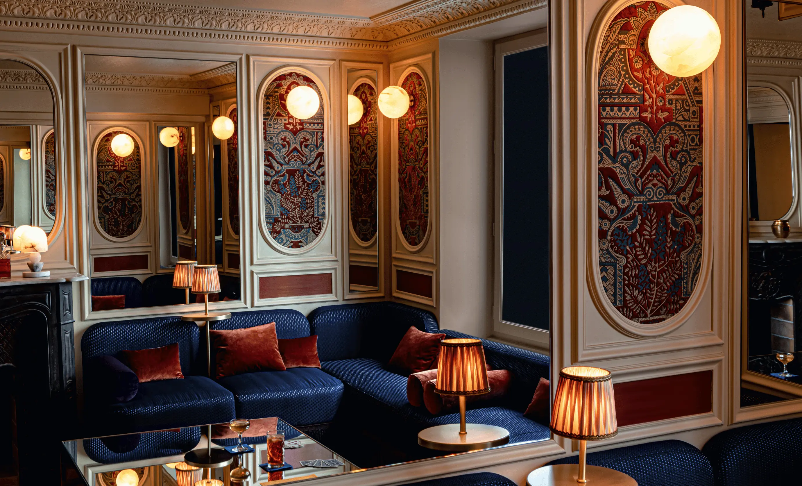 Luxurious blue velvet lounge with ornate wall paneling and warm ambient lighting at Experimental Group hotel.