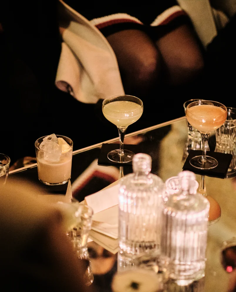 Selection of signature cocktails on a mirrored table, mixology experience by Experimental Group.