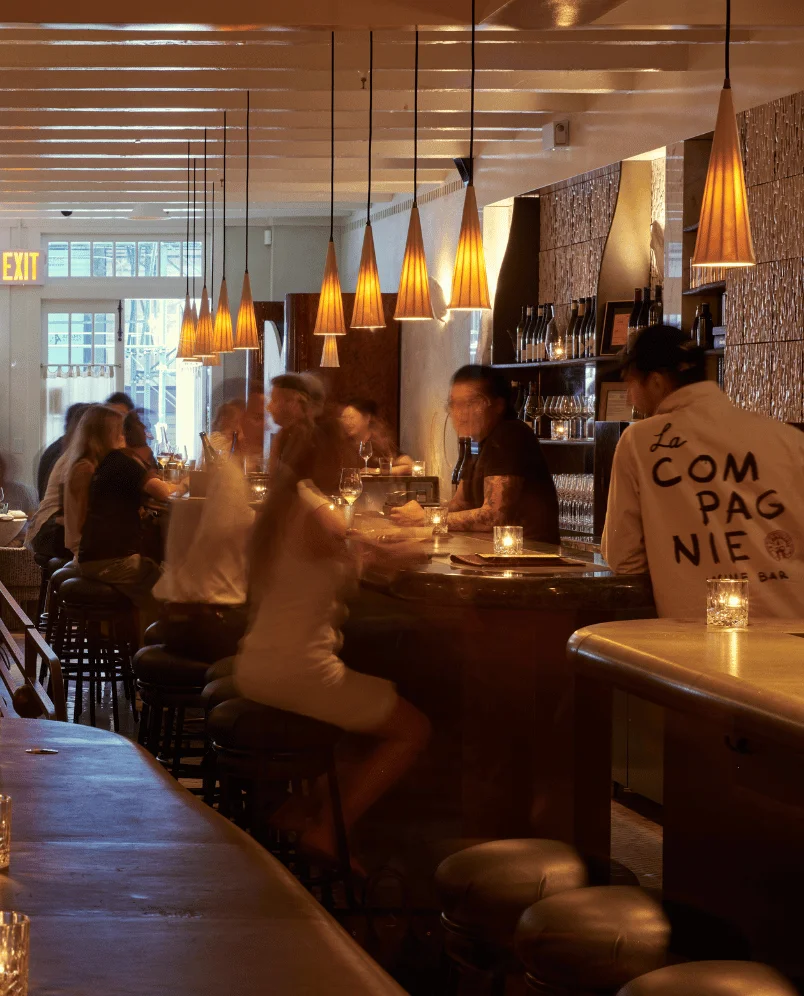 Warm and atmospheric lighting inside an Experimental Group bar, with customers at the counter.