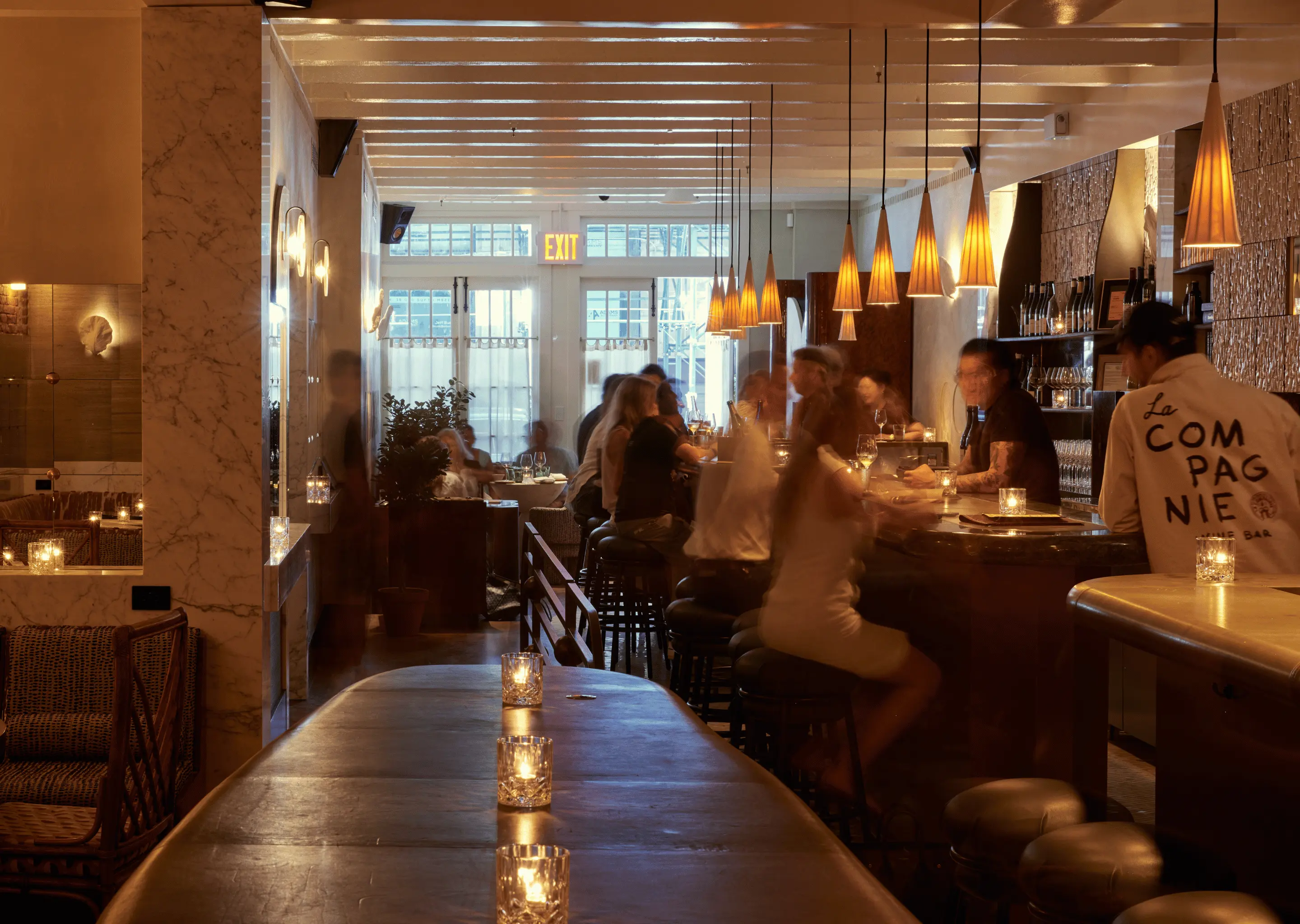 Overview of the interior of an Experimental Group bar with guests seated at the counter.