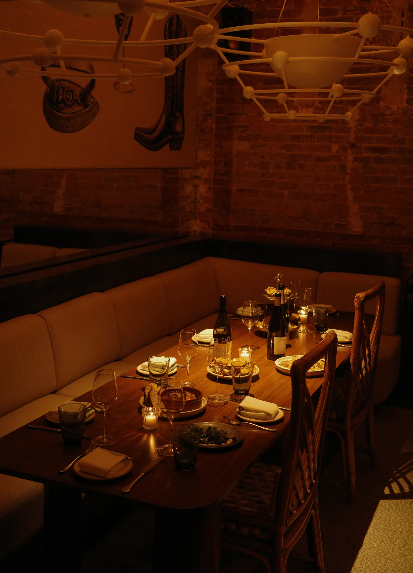 A cozy, private dining area with a long table, cushioned bench seating, and warm lighting at an Experimental Group restaurant.