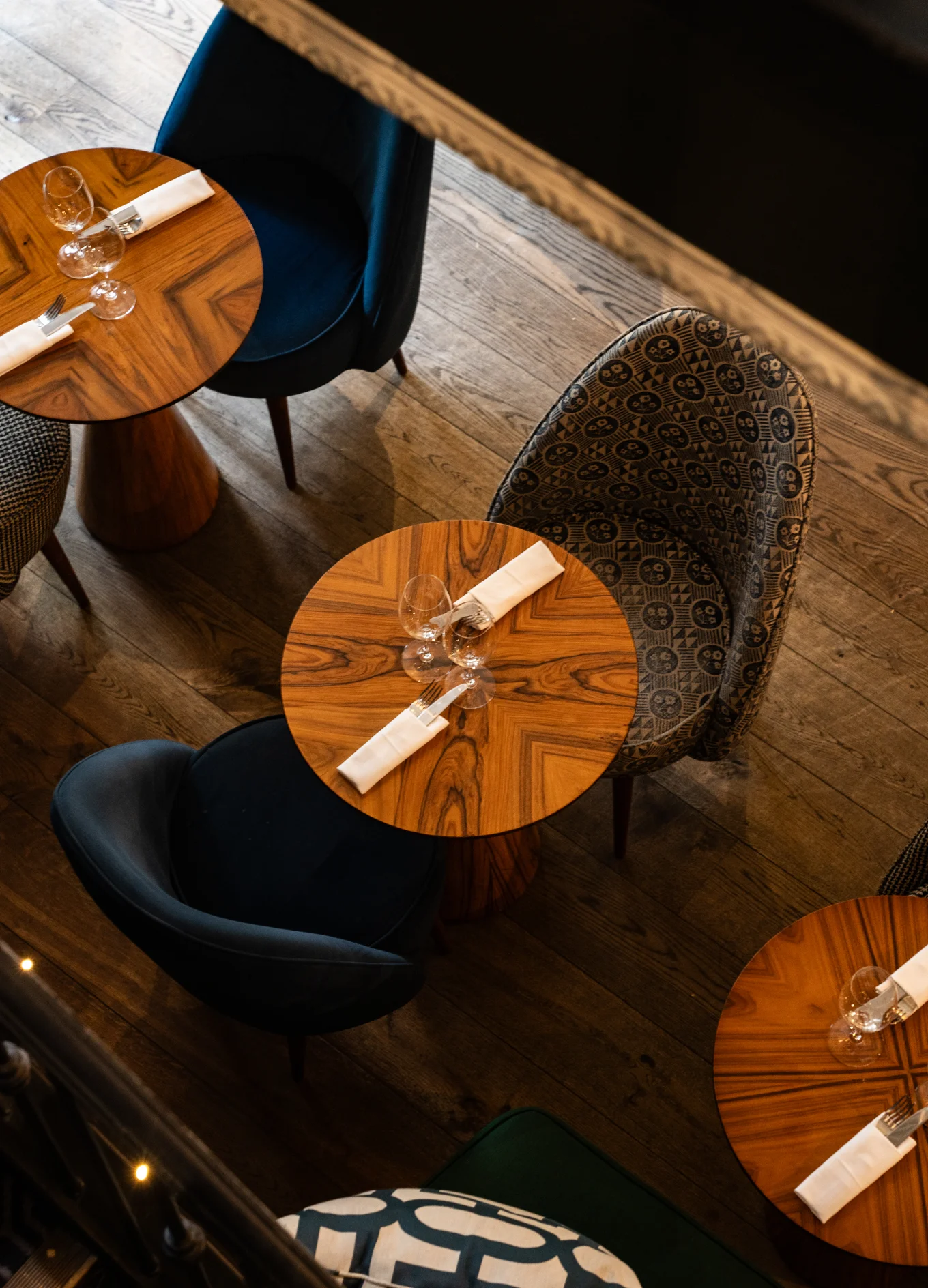 Intimate dining setting with wooden tables, upholstered chairs, and elegant table settings at an Experimental Group location.