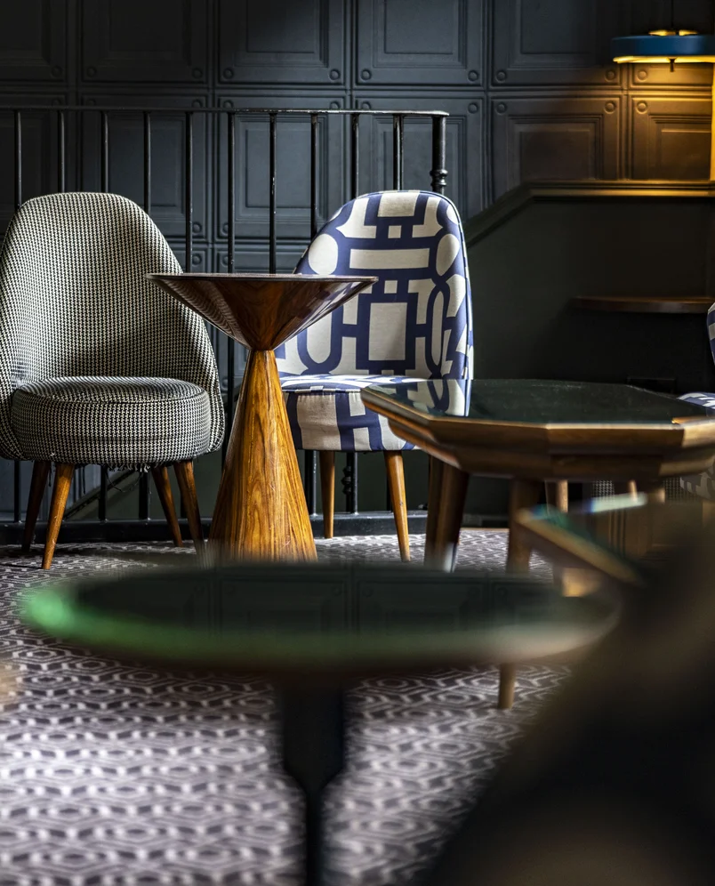 Interior design details featuring mid-century style chairs and a sculptural wooden table at an Experimental Group property.