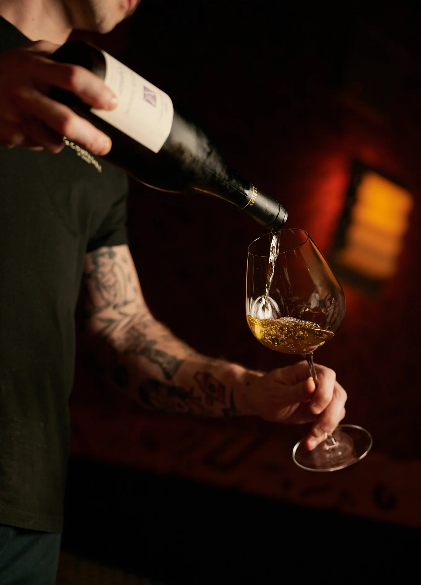 Bartender pouring a fine wine into a crystal glass in the sophisticated setting of an Experimental Group cocktail bar.