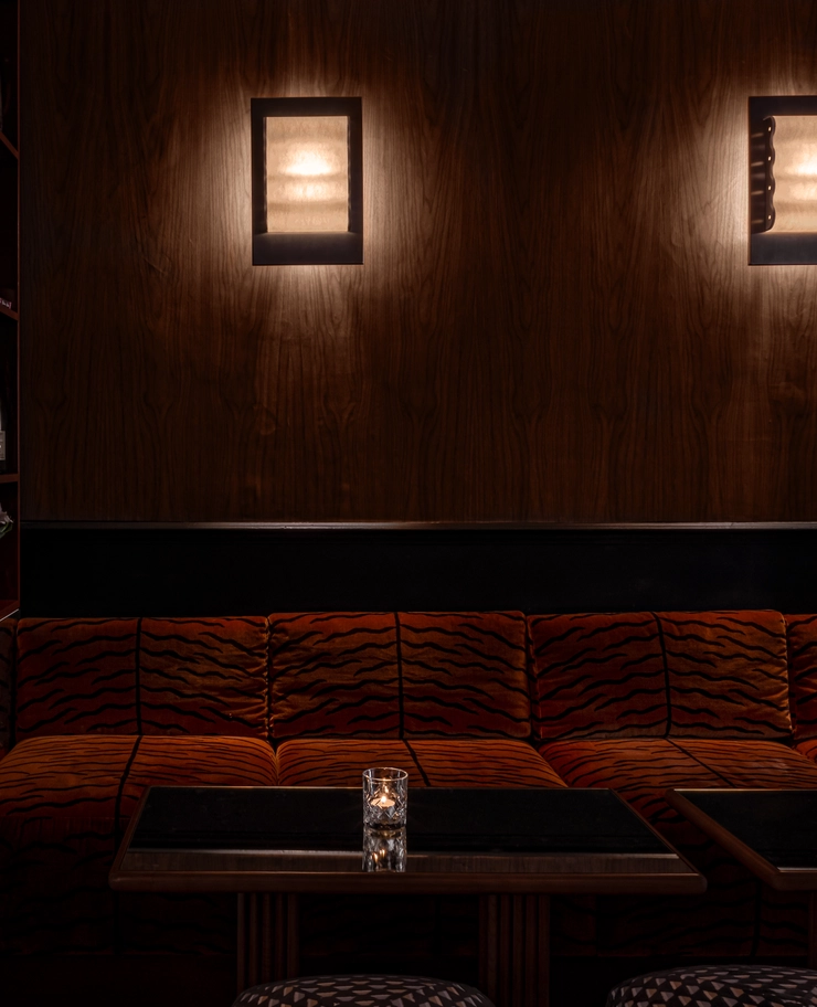 Cozy seating area with tiger-print velvet sofa and a lit candle on a dark table, showcasing the signature design of an Experimental Group establishment.