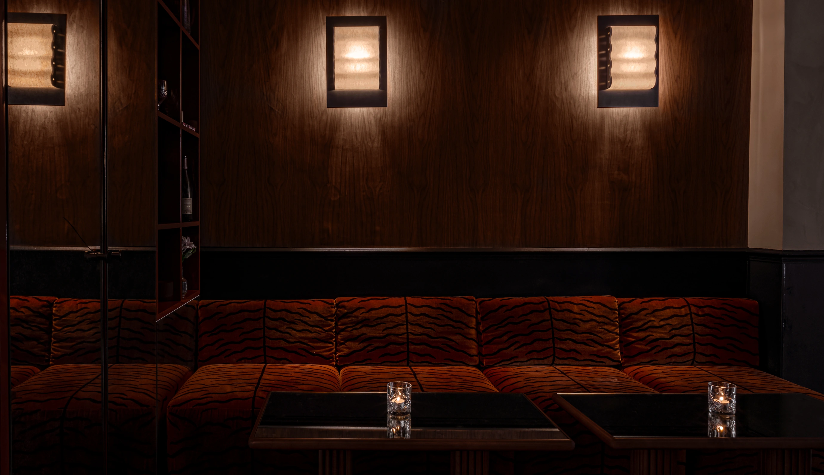 Interior view of an intimate Experimental Group lounge featuring plush tiger-patterned velvet seating and warm ambient wall lighting.