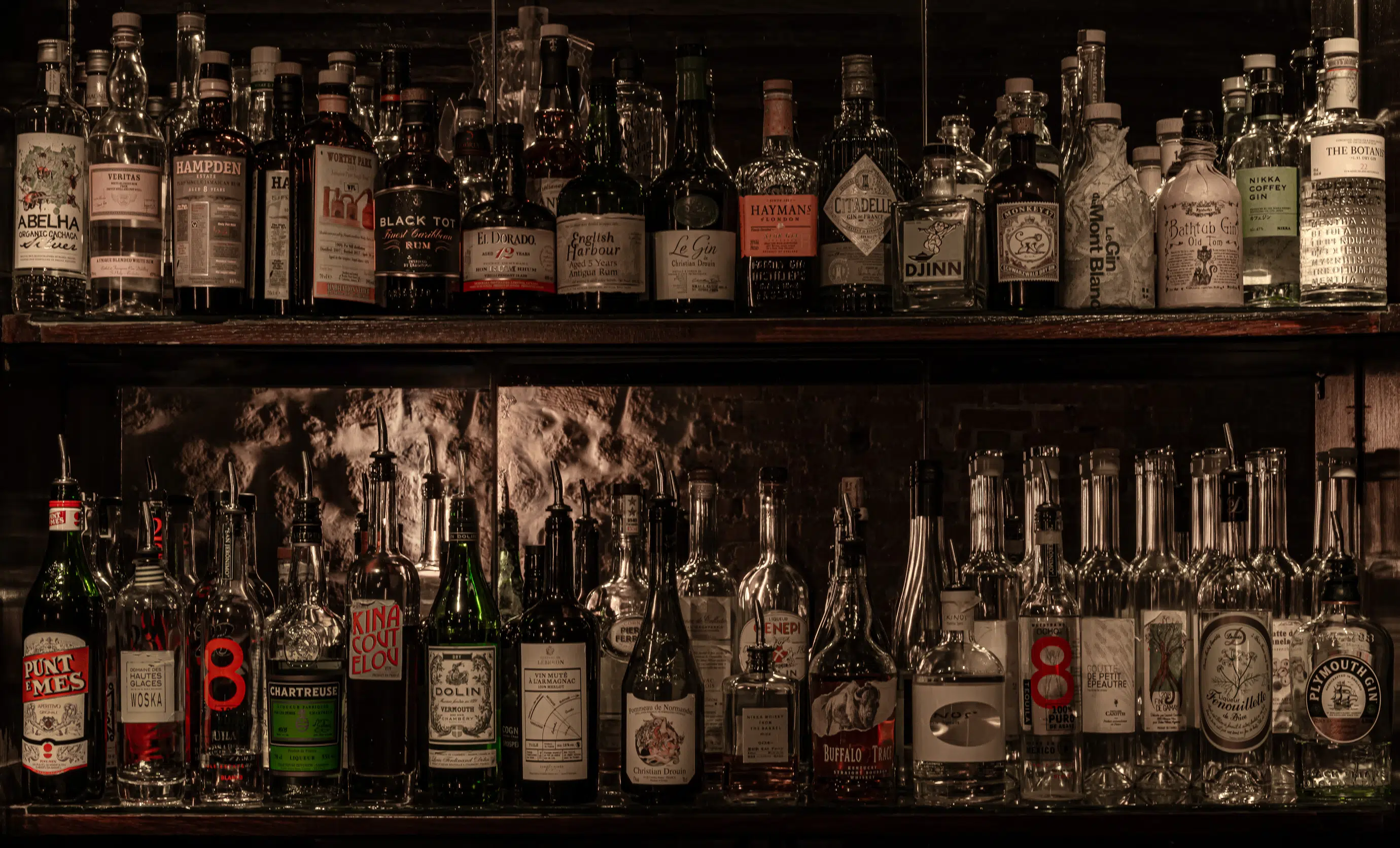 Carefully curated selection of premium spirits and liqueurs on the backlit bar shelves at Experimental Cocktail Club.