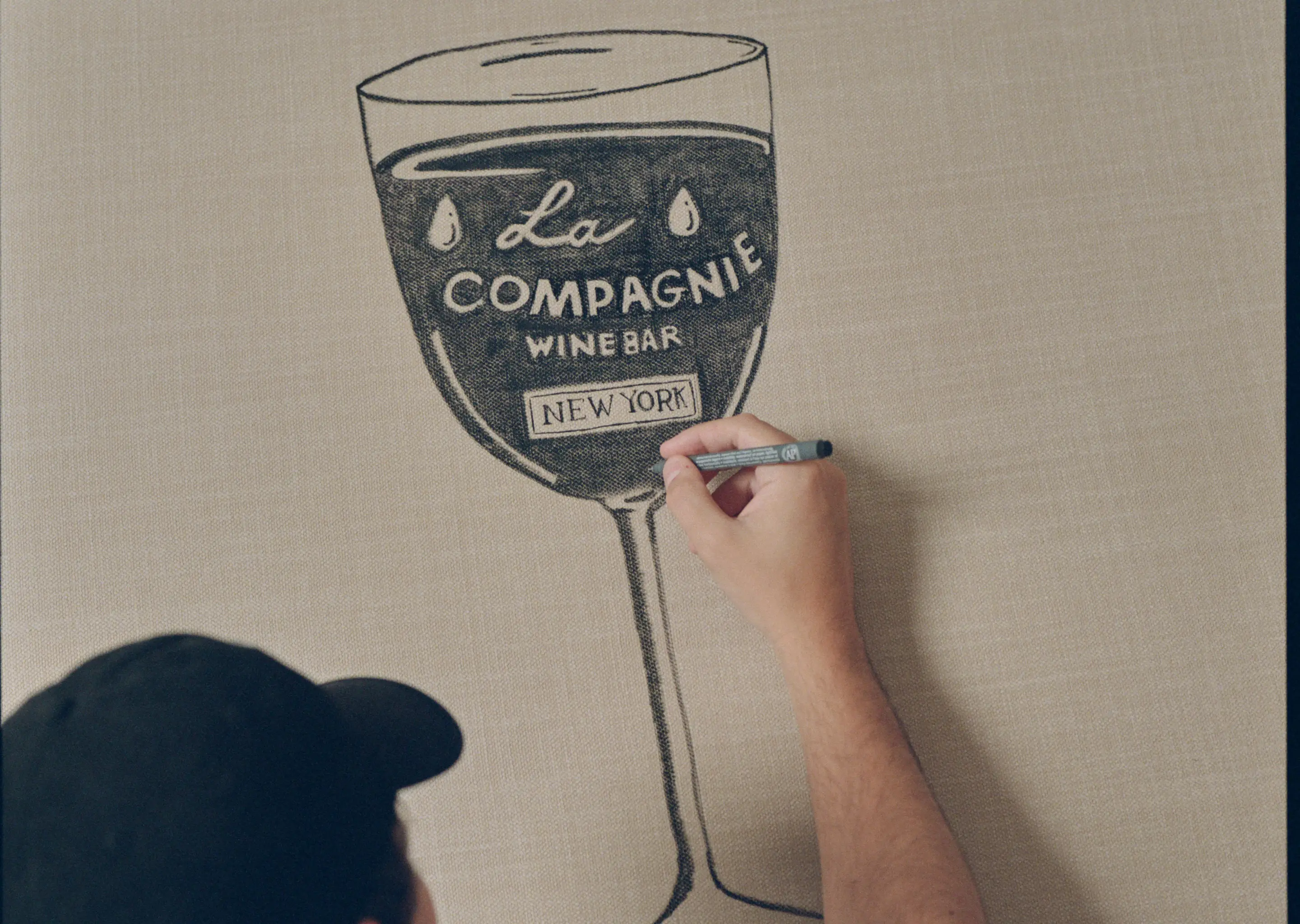Designer hand sketching the La Compagnie Wine Bar logo for Experimental Group in New York.