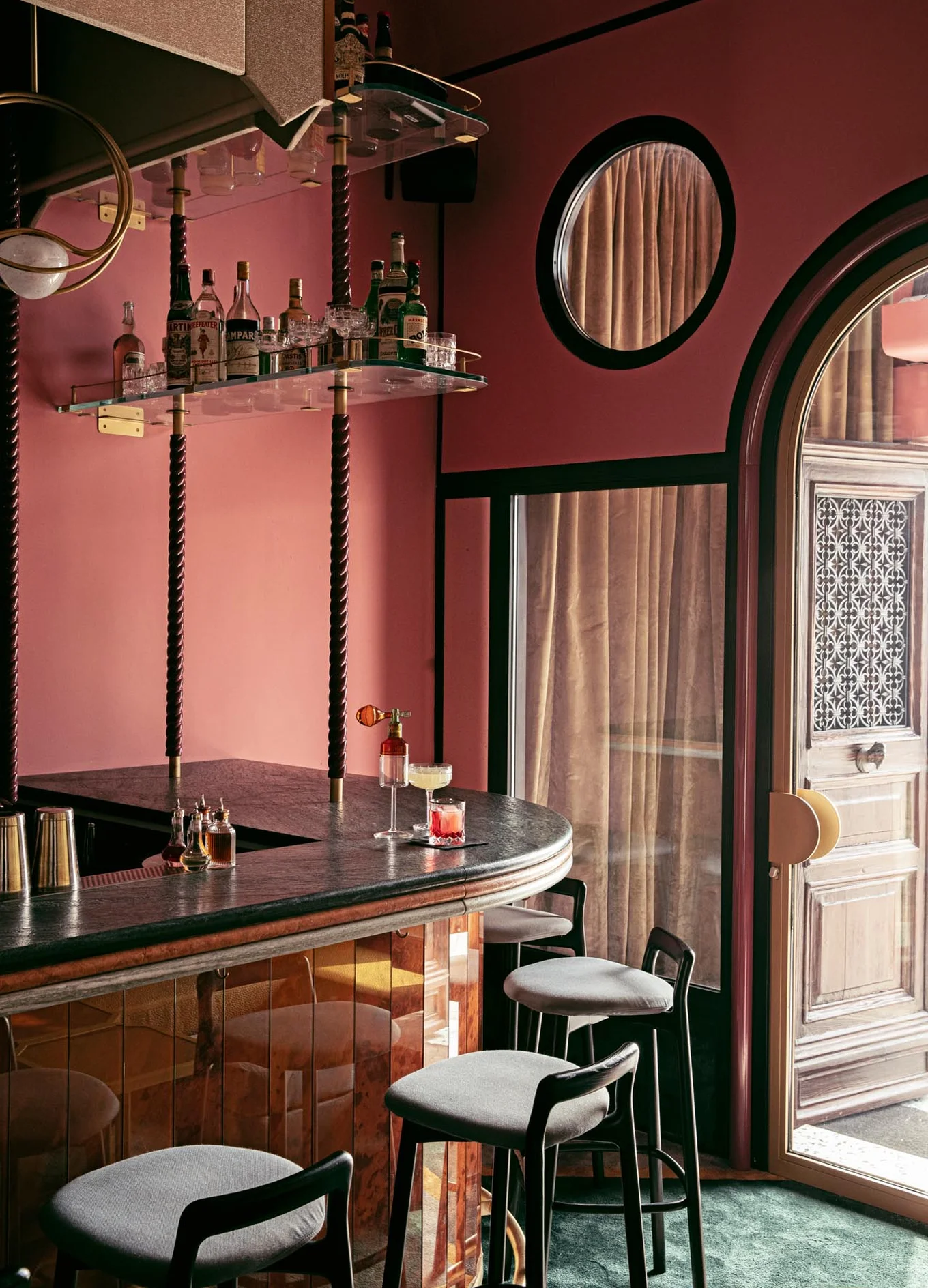 Overview of an Experimental Group bar interior with unique architecture, circular window, and velvet details.
