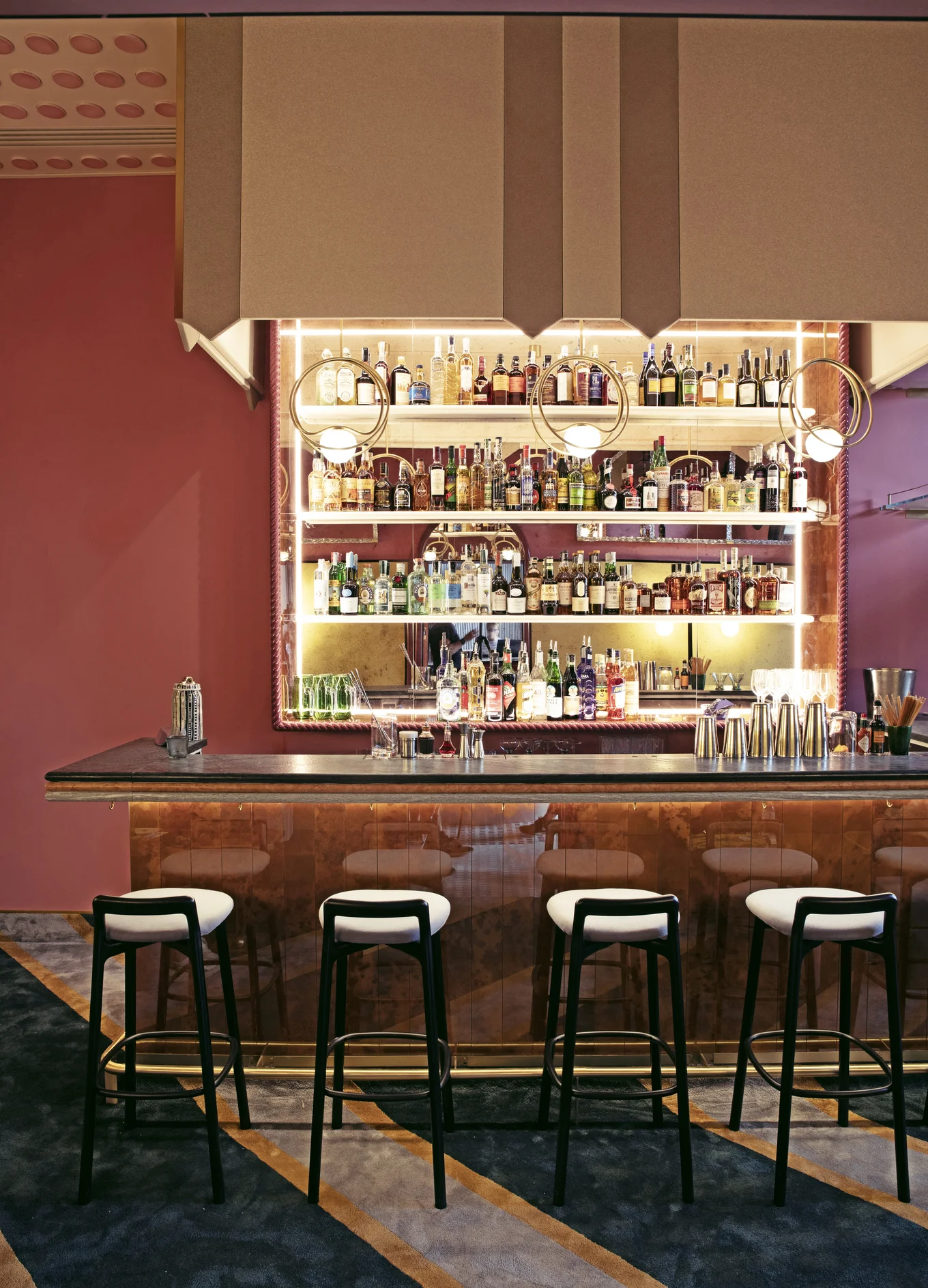 Elegant and stylish cocktail bar by Experimental Group, decorated in pink tones with backlit shelves.