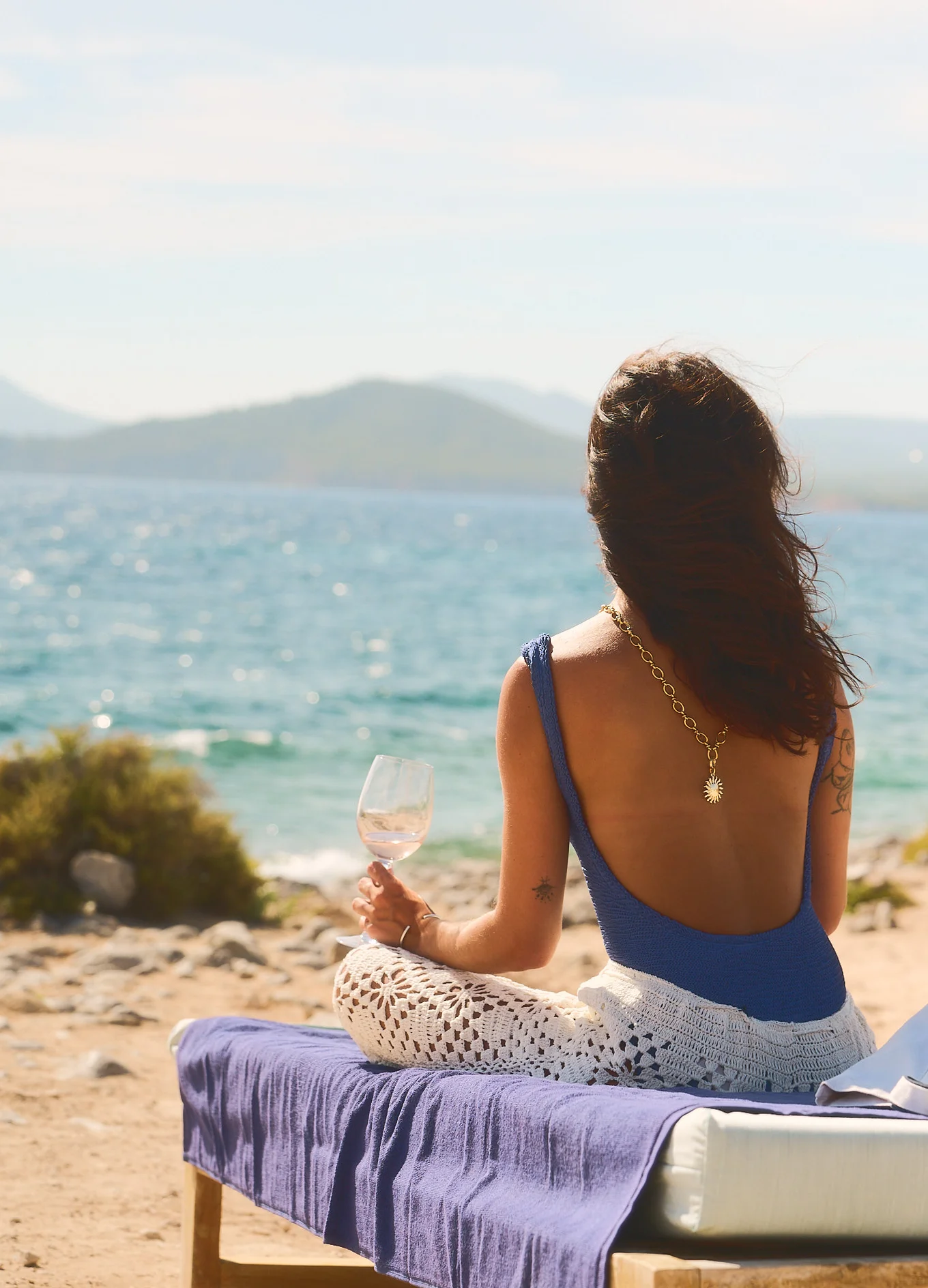 Woman relaxing with a glass of rosé wine facing the sea, lifestyle experience at the Experimental Group.