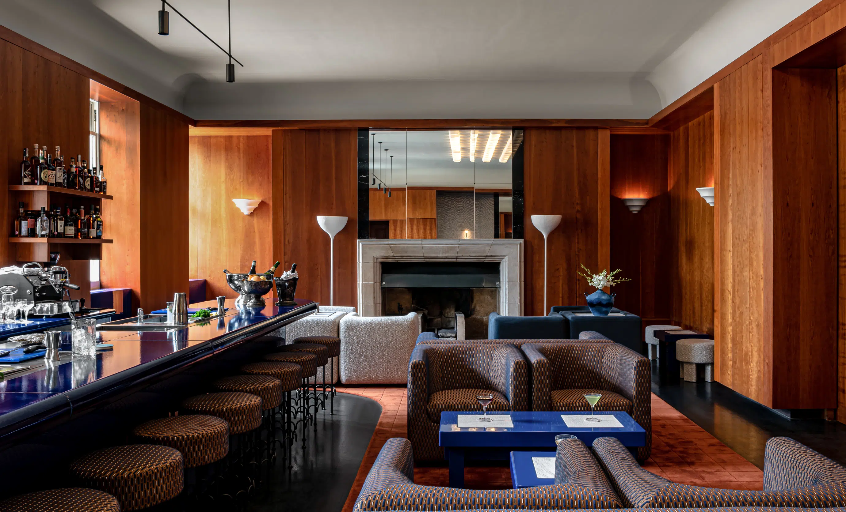 Overview of the designer bar with stools and the warm lounge area at Cowley Manor Experimental, Cotswolds.