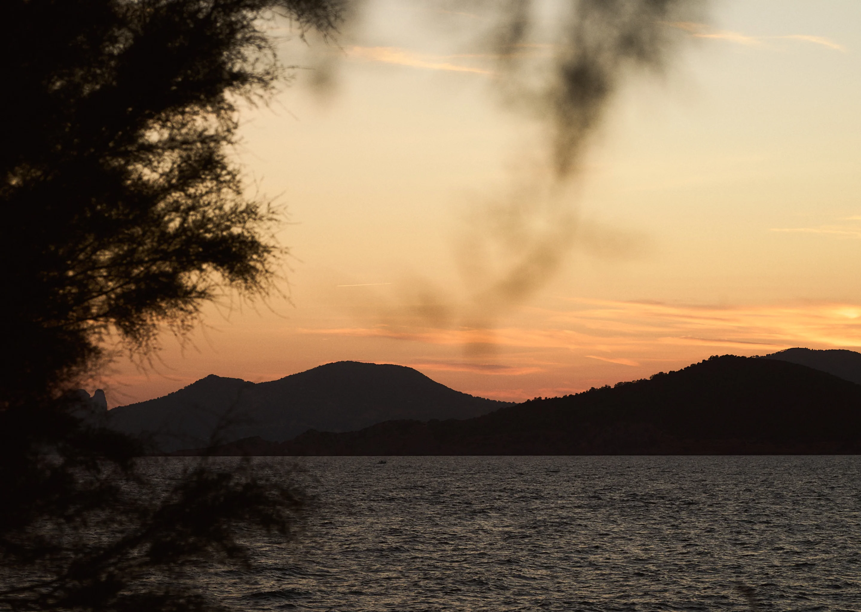 Serene landscape featuring a dramatic sunset over the hills and water at an Experimental Group venue.