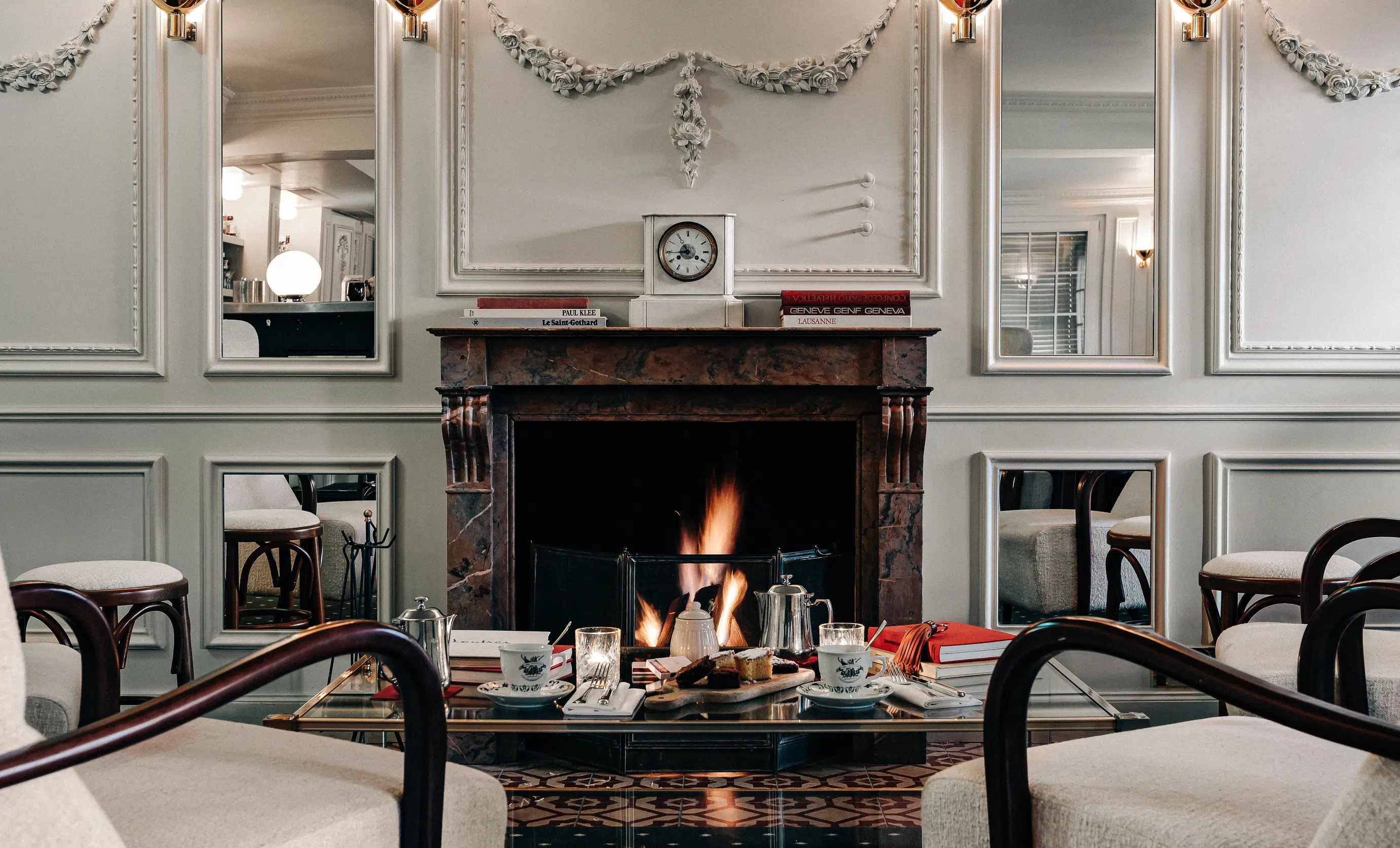 Afternoon tea and snacks served on a glass table in front of a warm fireplace at the Experimental Cocktail Club, Verbier.
