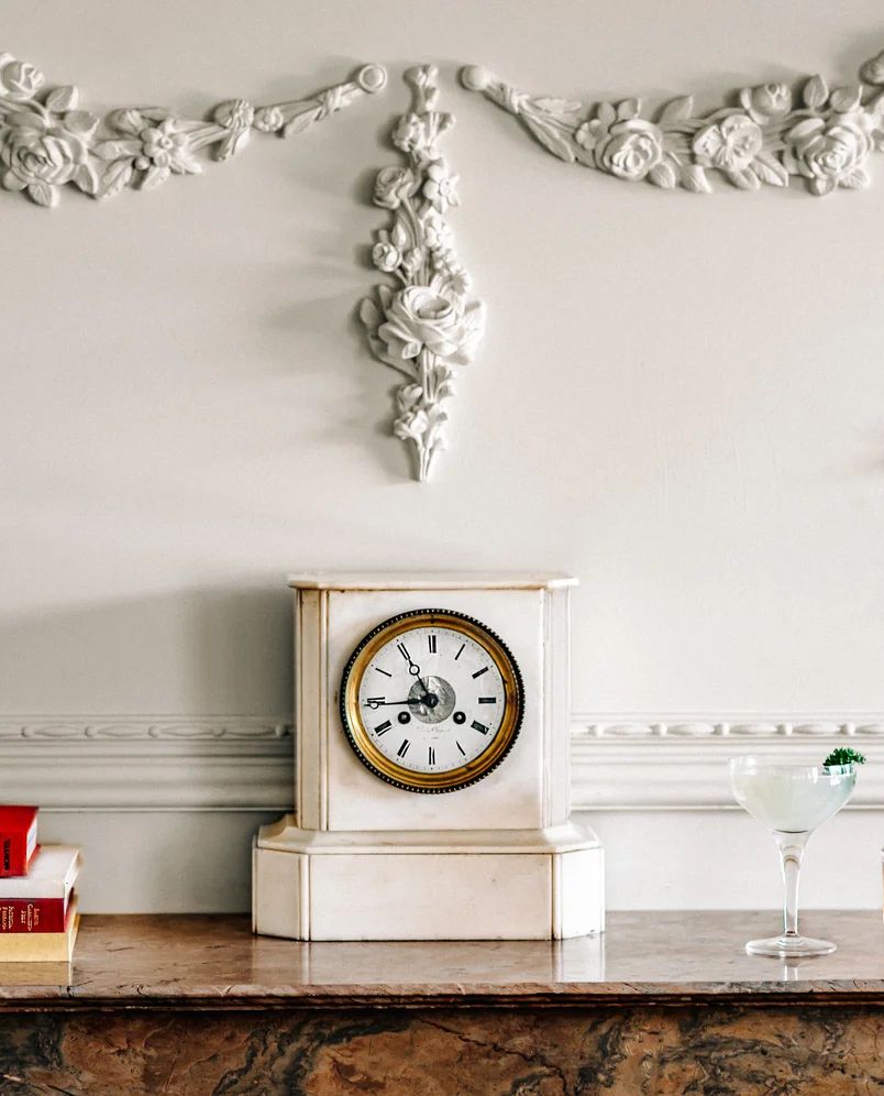 Vintage clock on a marble fireplace mantel in the elegant lounge of the Experimental Cocktail Club in Verbier, Switzerland.