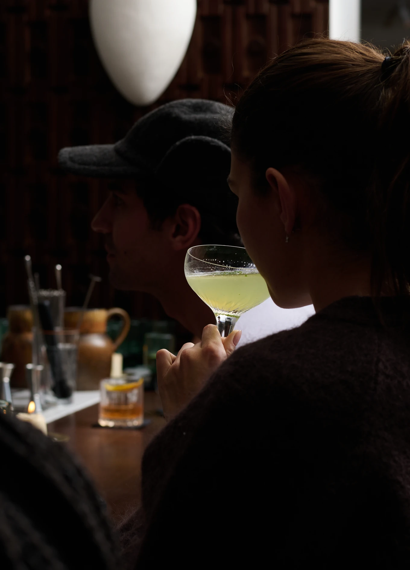 A guest holding an elegant cocktail at the bar of the Experimental Chalet, showcasing the intimate atmosphere.