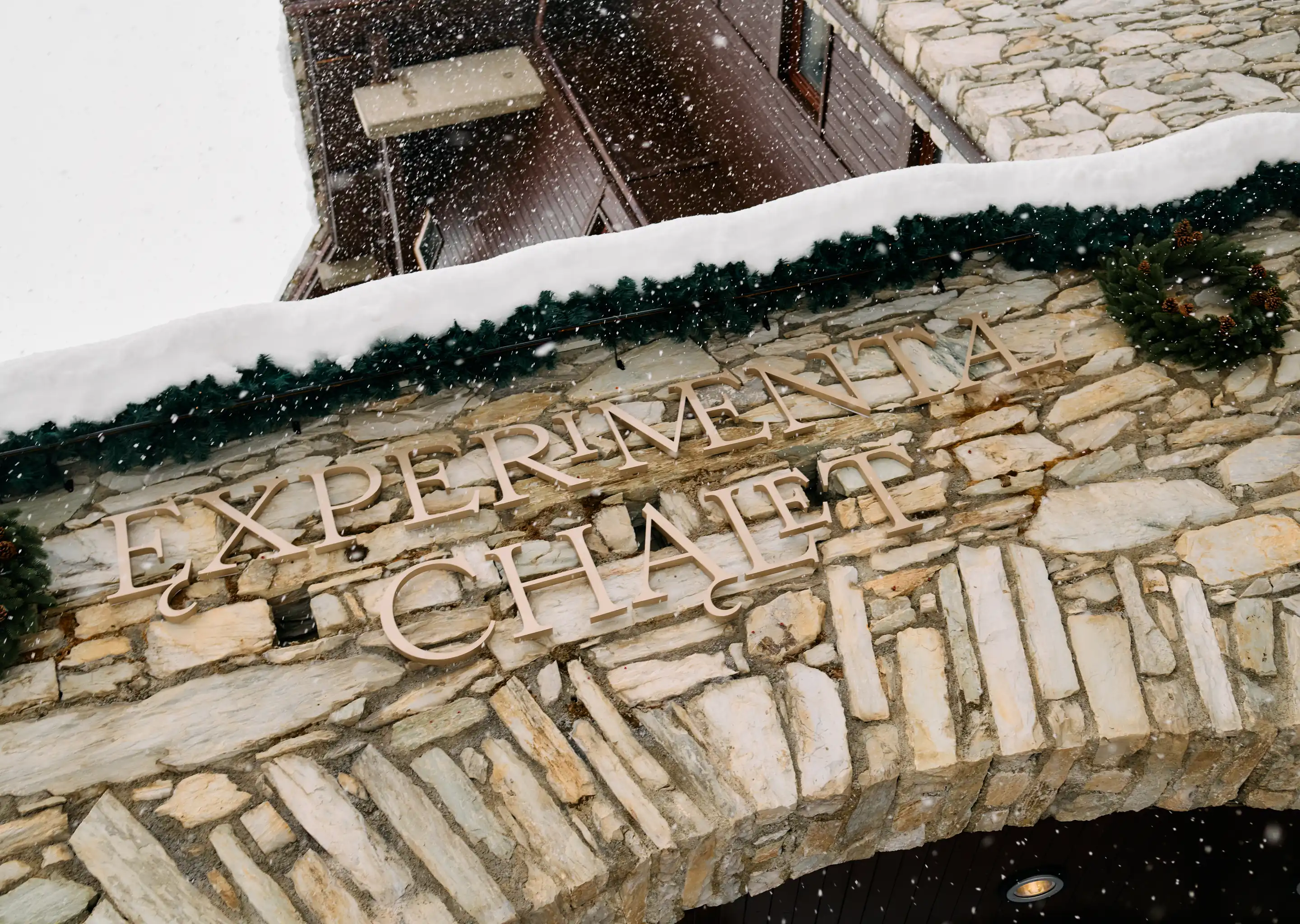 Decorative Christmas wreath and snowy stone exterior details at the Experimental Chalet in the mountains.