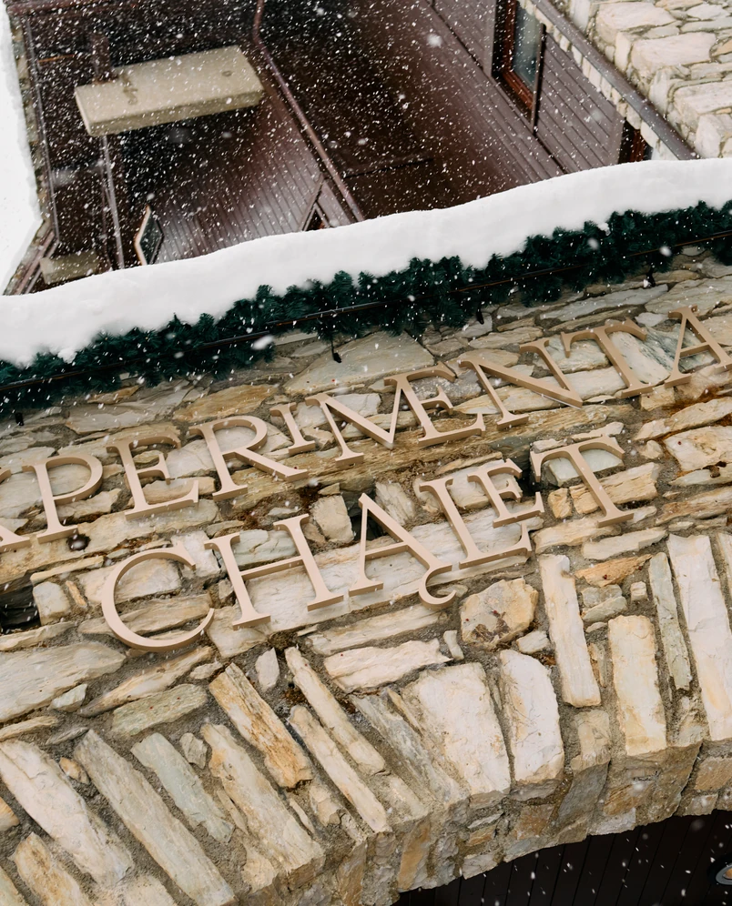 Stone facade signage of Experimental Chalet in the snowy French Alps with a cozy winter atmosphere.