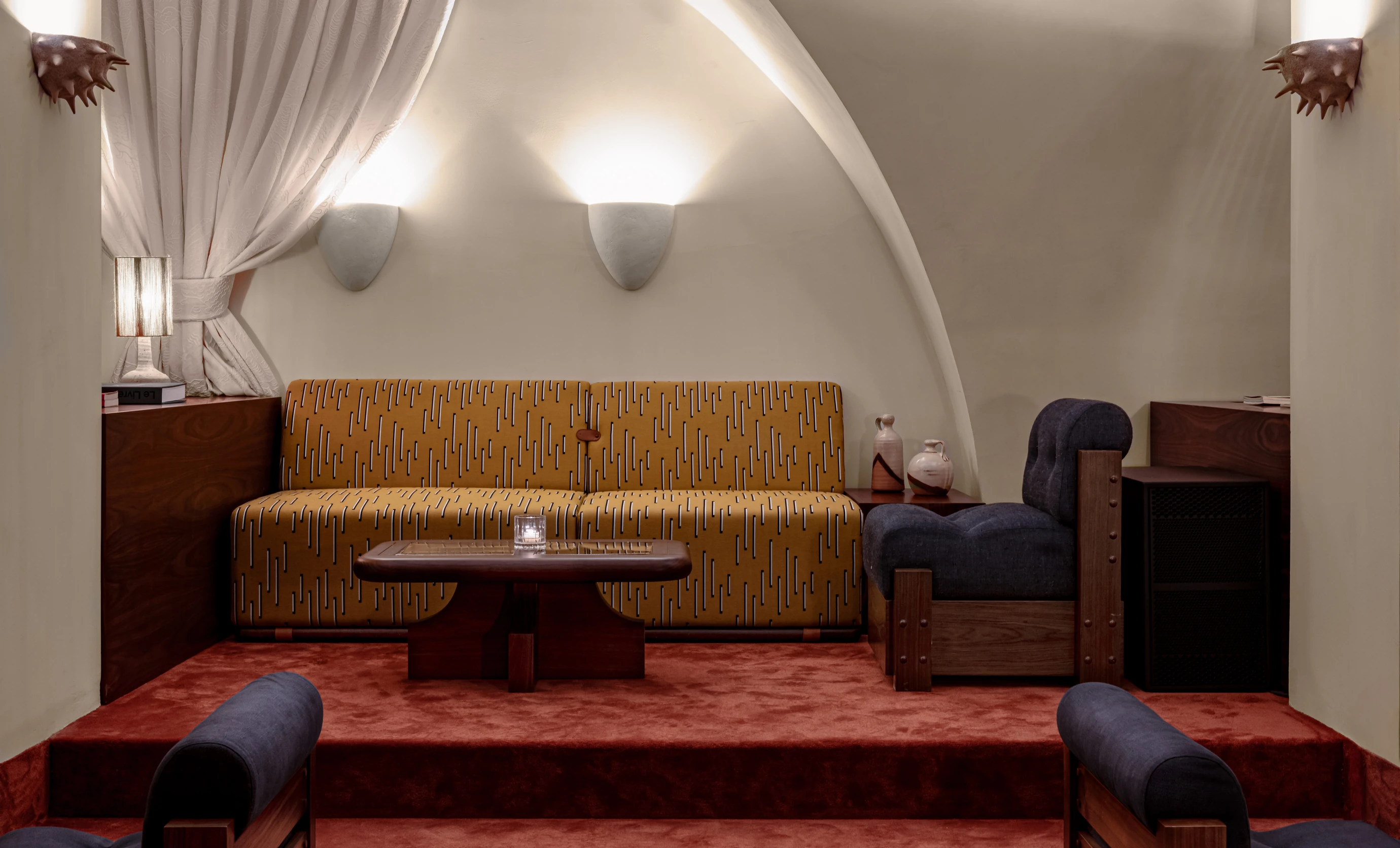 Cozy lounge corner at the Experimental Cocktail Club featuring vintage-inspired patterns, warm lighting, and comfortable seating.