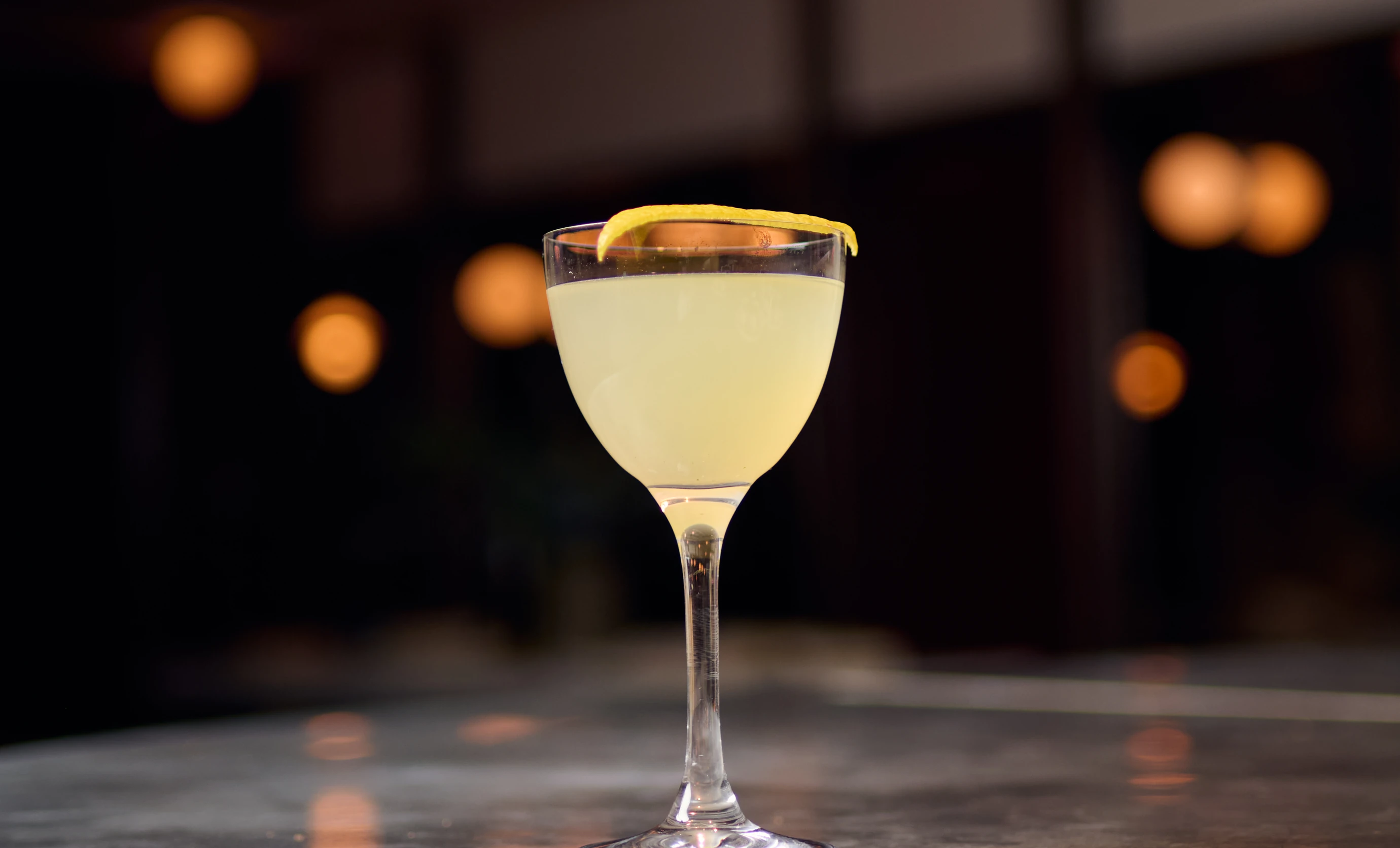 A beautifully presented citrus-based cocktail with a lemon twist served at the Experimental Cocktail Club.