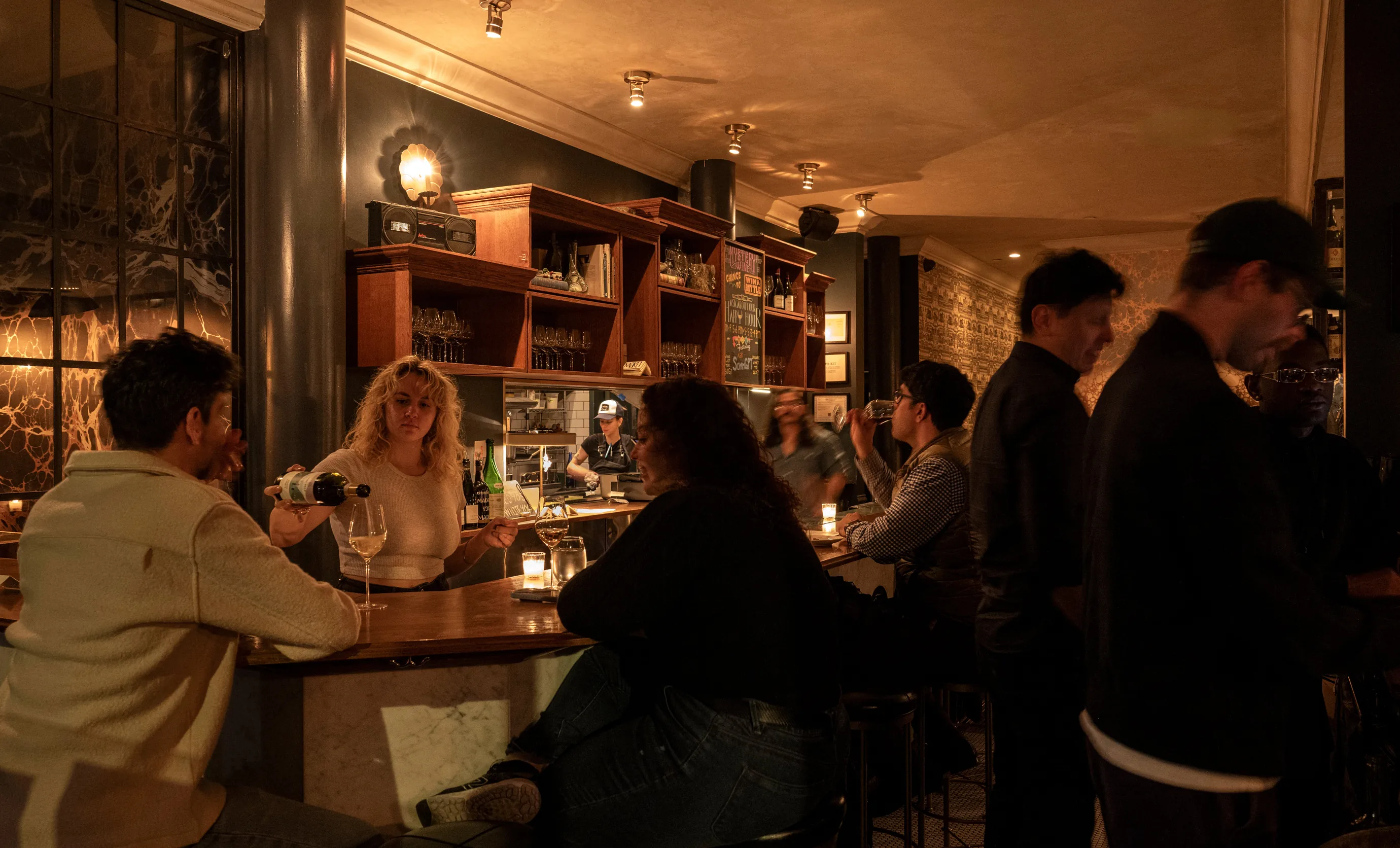 Un barman sert du vin à un invité de l'élégant Experimental Cocktail Club, mettant en valeur le service professionnel et l'ambiance sociale.