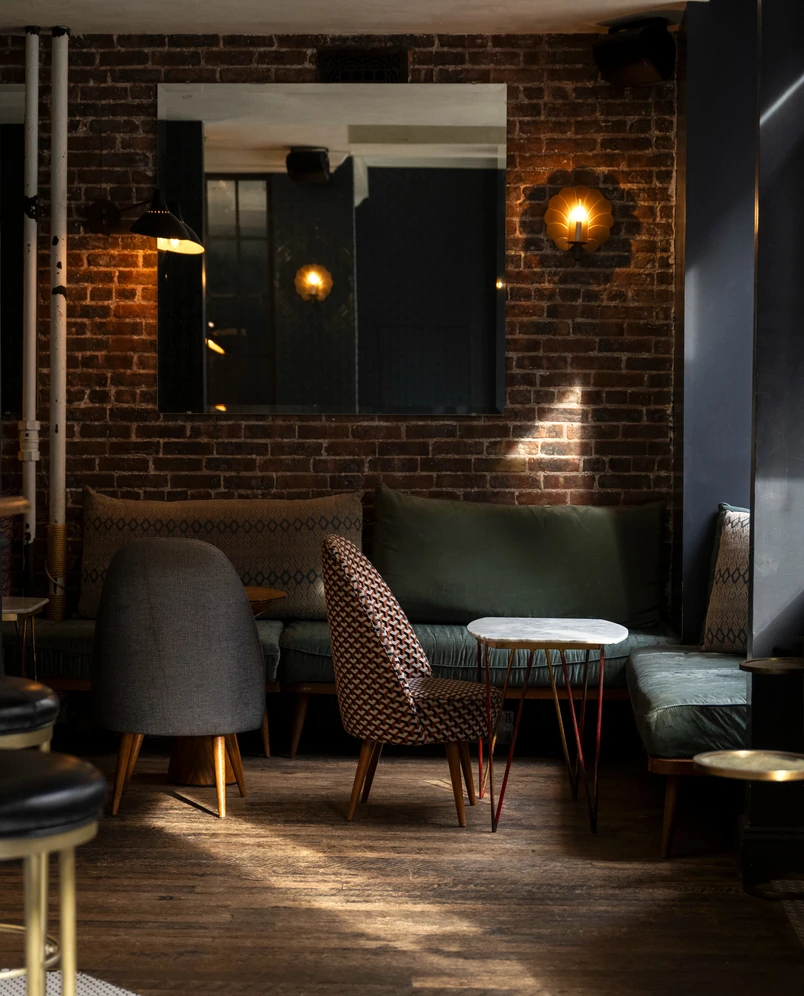 Salon confortable avec mur de briques apparentes et mobilier design au sein d'une salle Experimental Group.