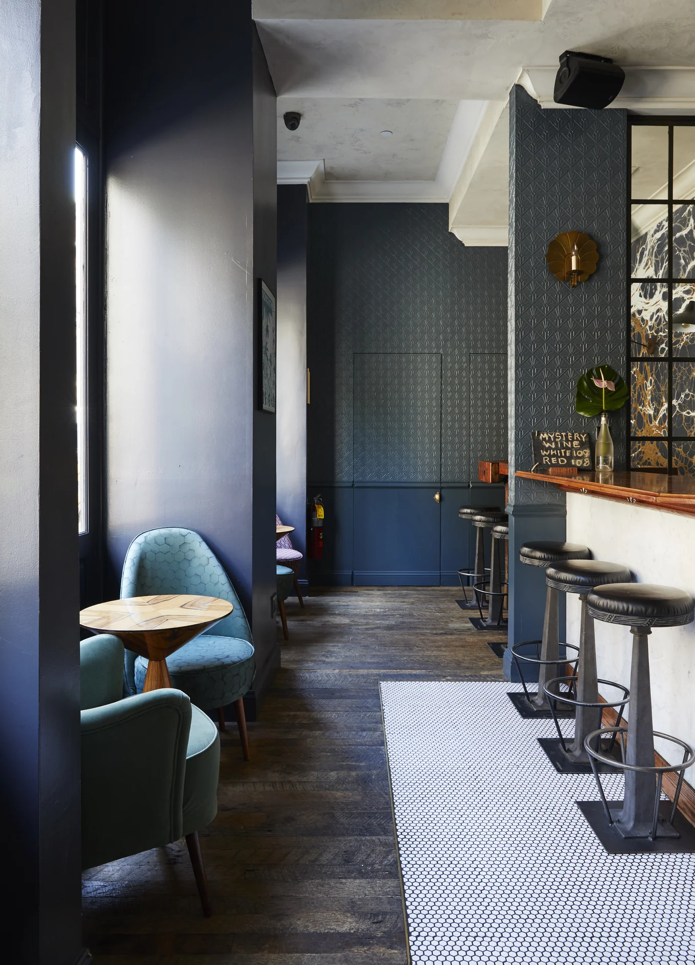 Elegant and cozy atmosphere of an Experimental Group bar with blue velvet armchairs and a modern bar counter.