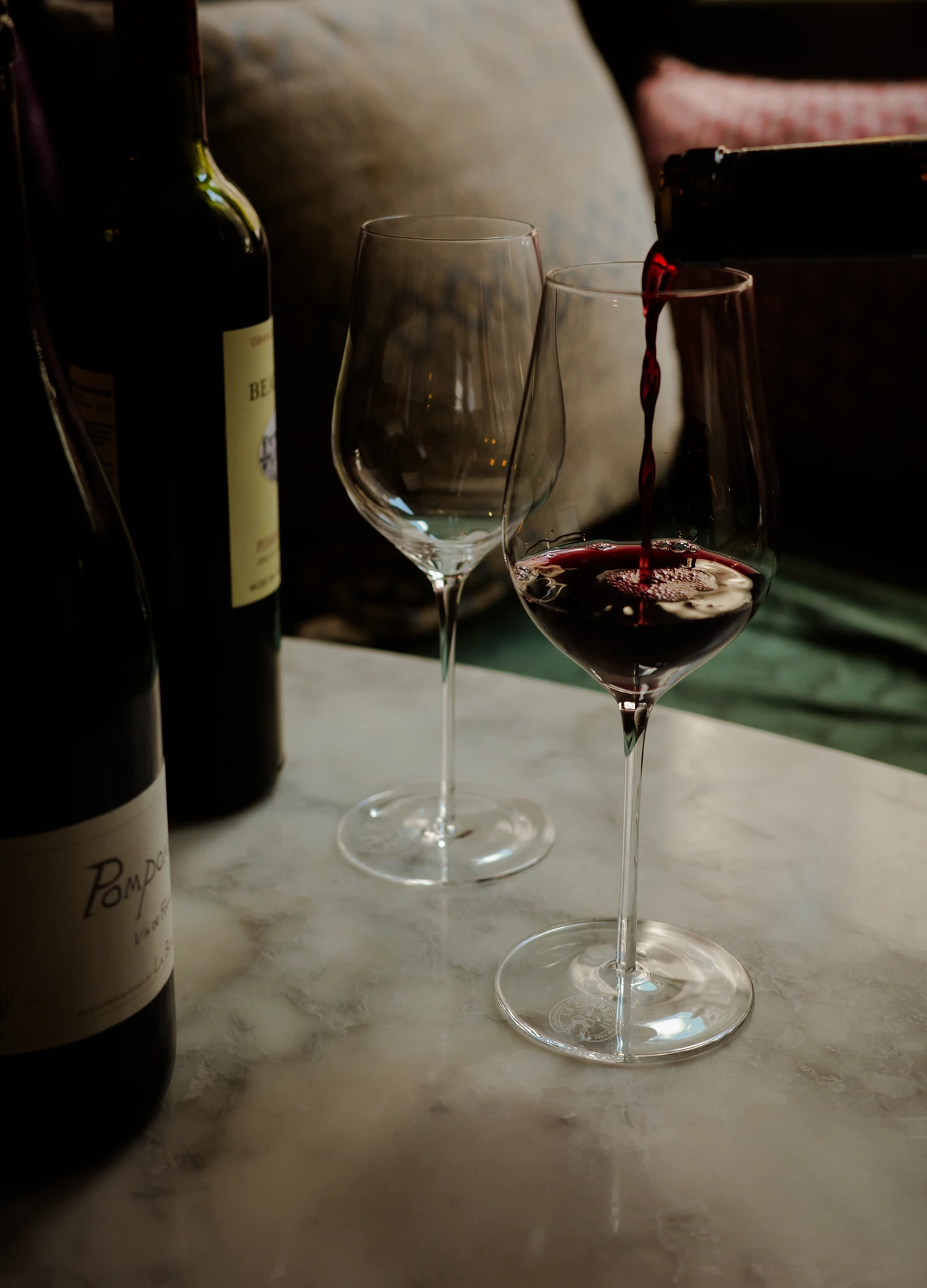 Pouring red wine into a crystal glass at an Experimental Group lounge, reflecting the brand's focus on high-quality gastronomy.