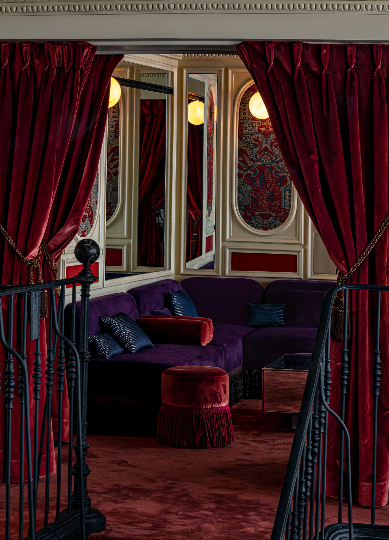 Cozy, private velvet corner booth behind heavy red curtains inside an Experimental Group boutique hotel.