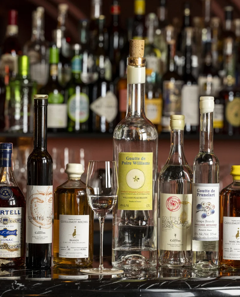 Selezione di liquori artigianali, tra cui Goutte de Poire Williams, esposta nel bar Experimental Group.