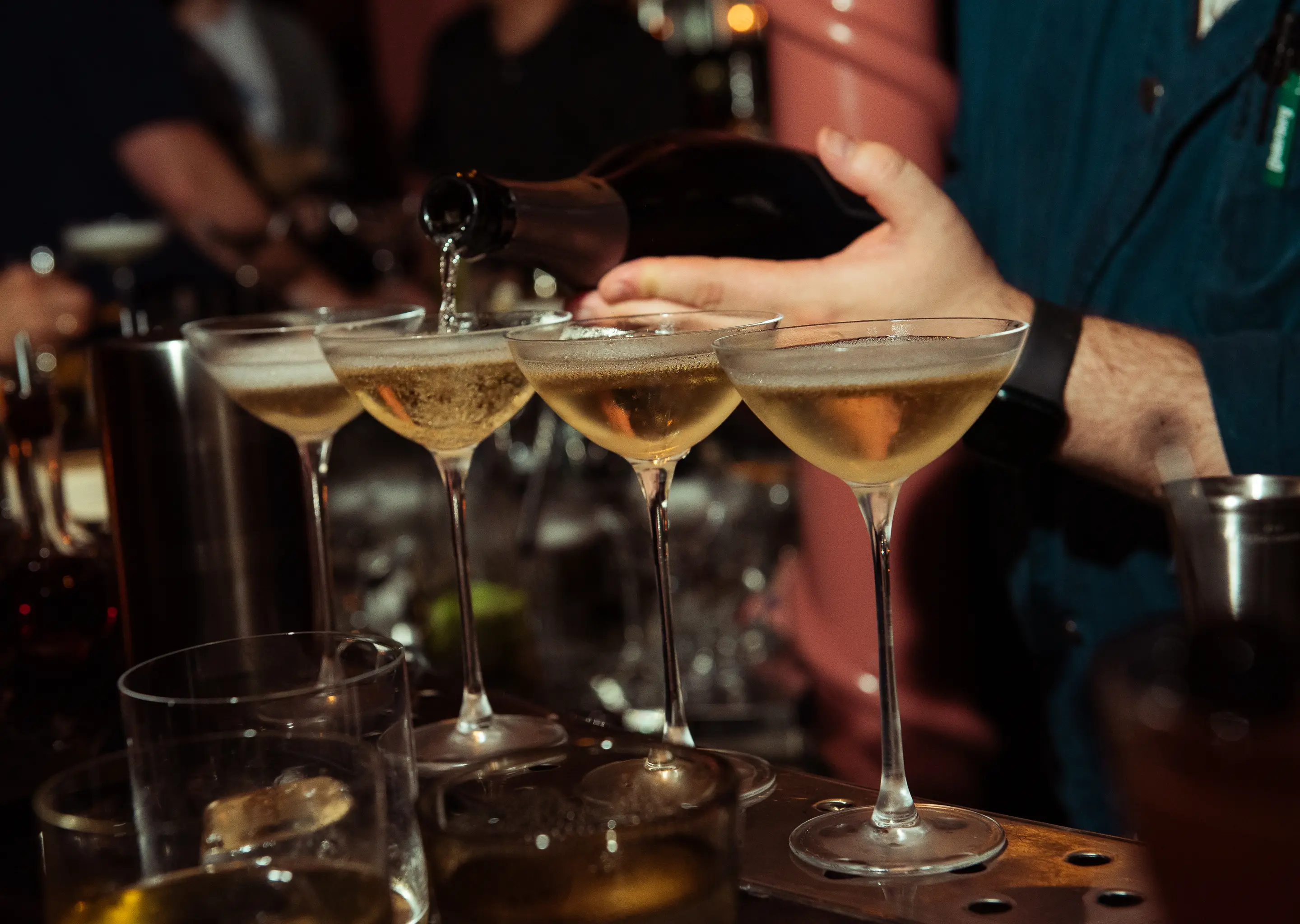 Barman servindo champanhe em uma fileira de cupês no elegante bar Experimental Group.