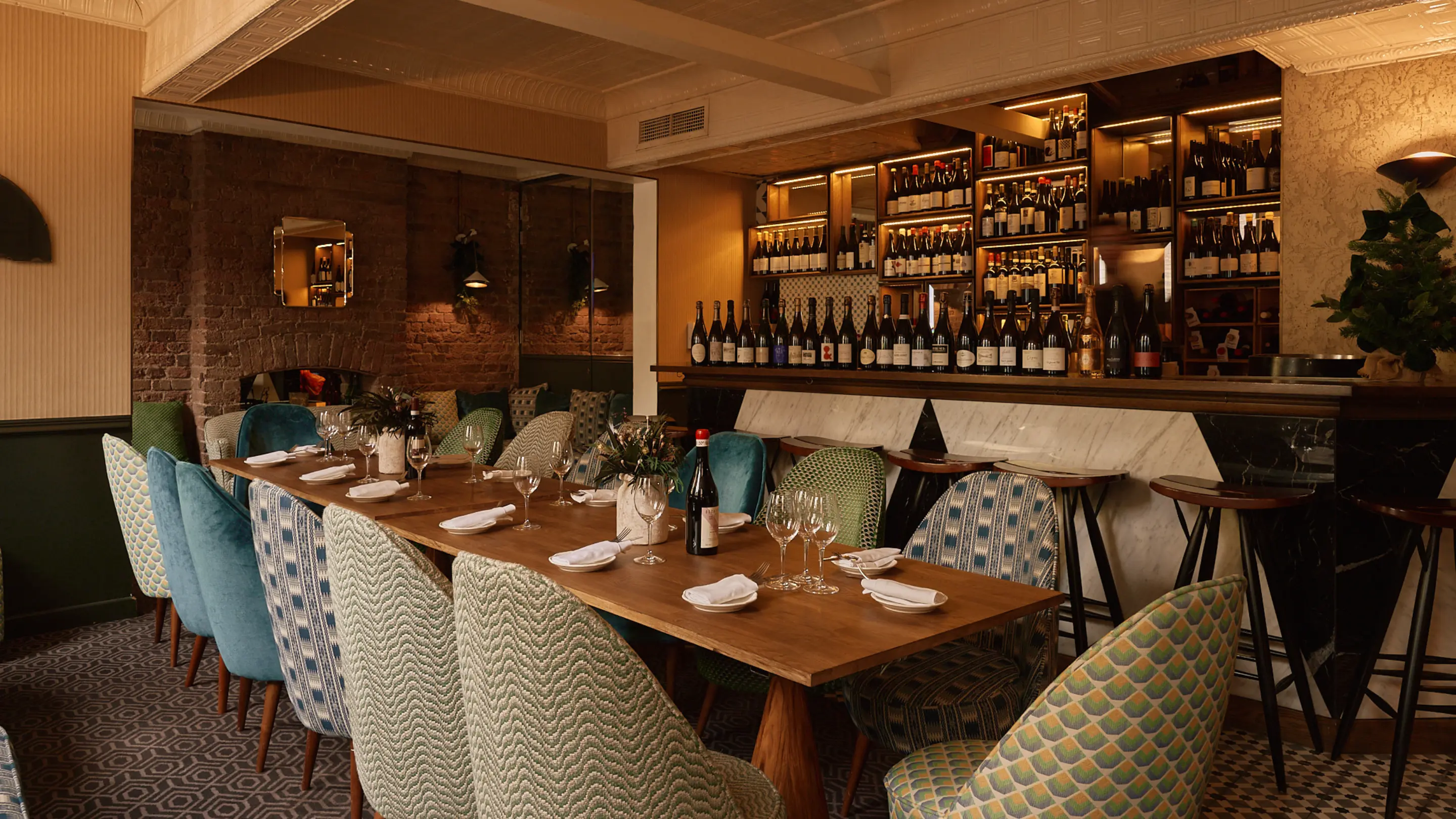 Elegant dining room with velvet chairs and wine wall at The Henrietta Hotel restaurant, London.