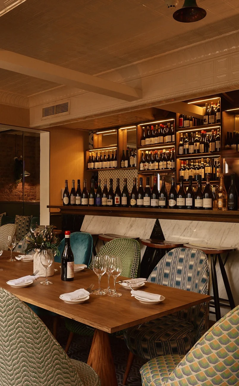 Set dining table with a bottle of wine at The Henrietta Hotel restaurant, London.