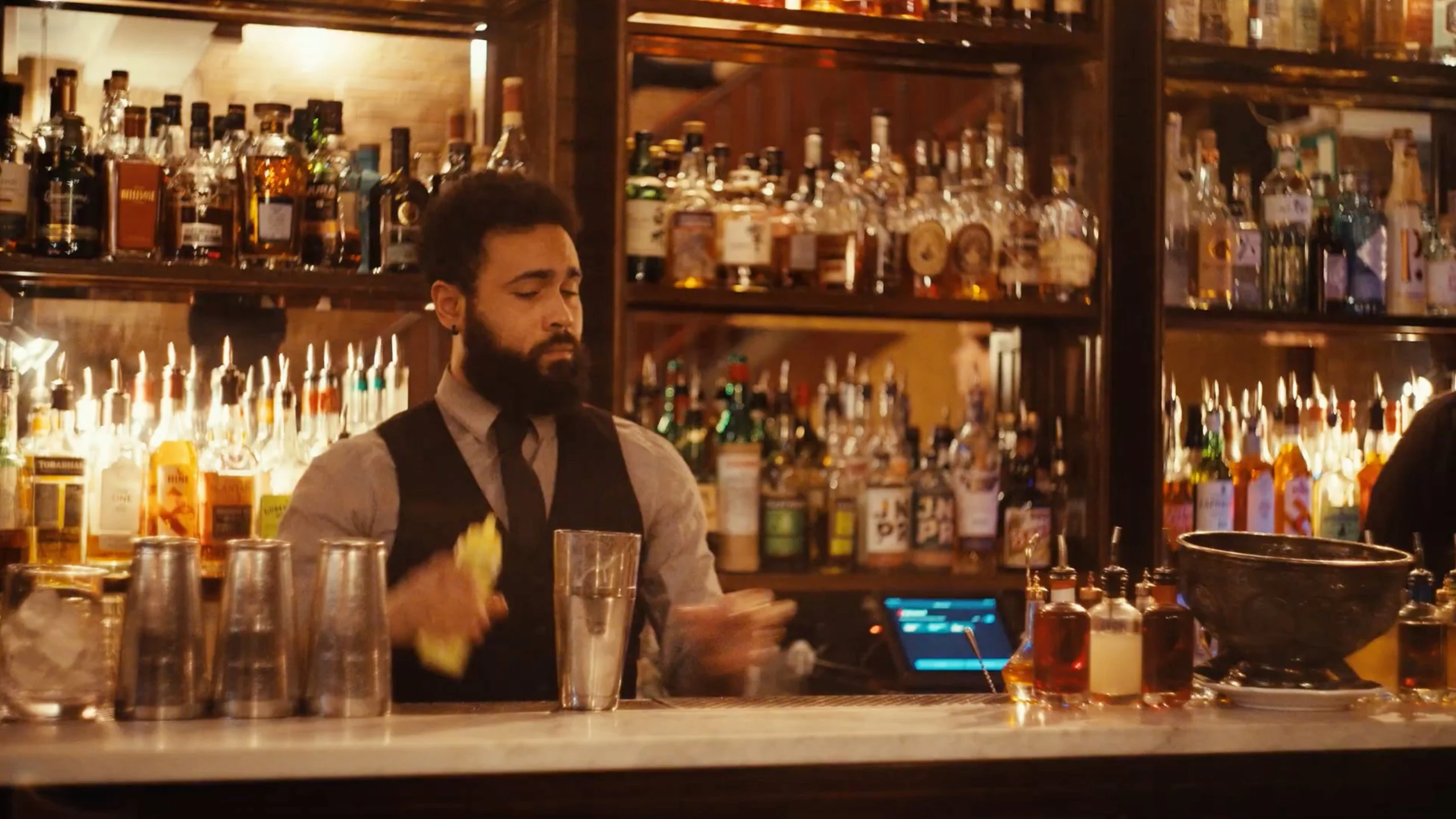Bartender preparing cocktails behind the bar at The Henrietta Hotel, London.