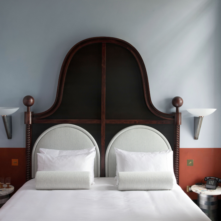Habitación en The Henrietta Hotel con cabecera de madera oscura y teléfono vintage, Londres.