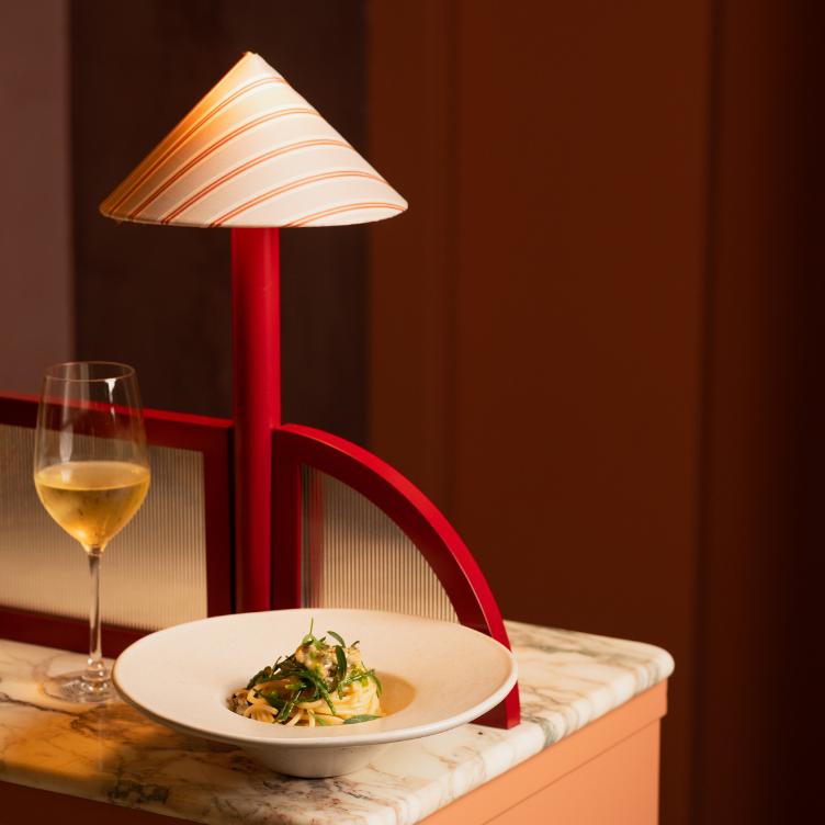 Plato de pasta gourmet, copa de vino y lámpara a rayas en el restaurante The Henrietta Hotel de Londres.