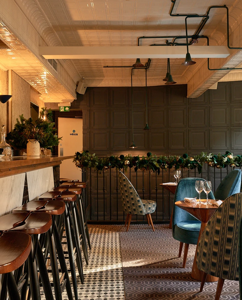 Stylish restaurant dining space with plush velvet chairs and festive holiday decorations at an Experimental Group hotel.
