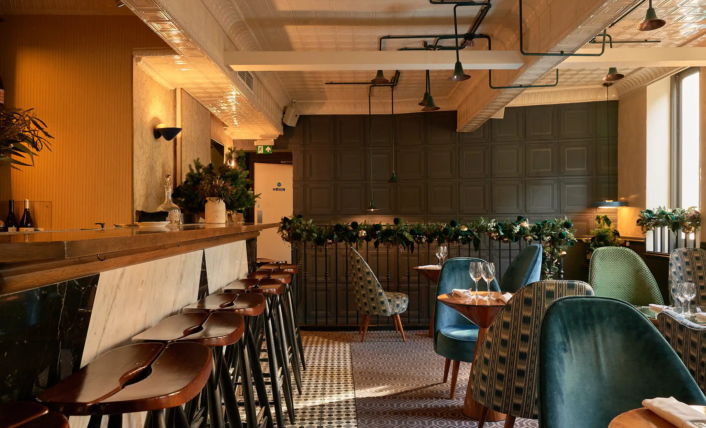 Sophisticated cocktail bar interior with wooden bar stools, patterned decor, and ambient lighting at an Experimental Group hotel.