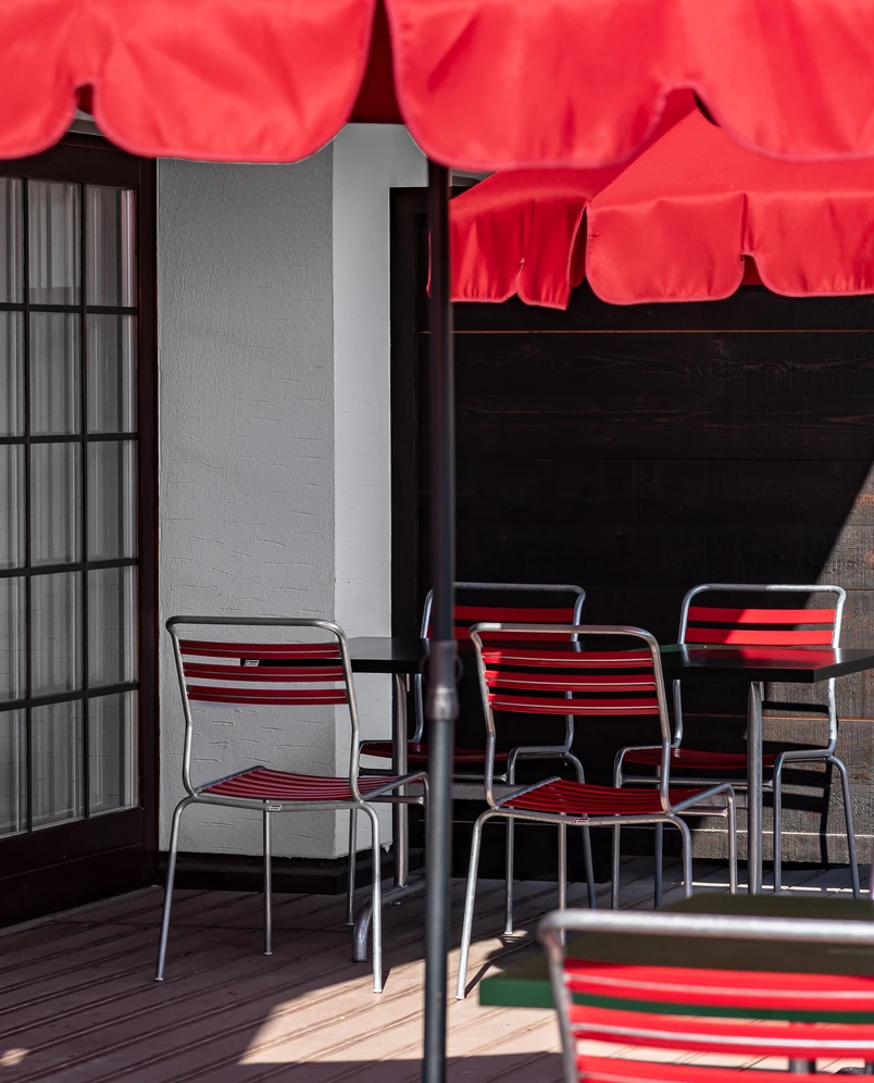 Outdoor terrace seating area with vibrant red chairs and parasols at an Experimental Group hotel.