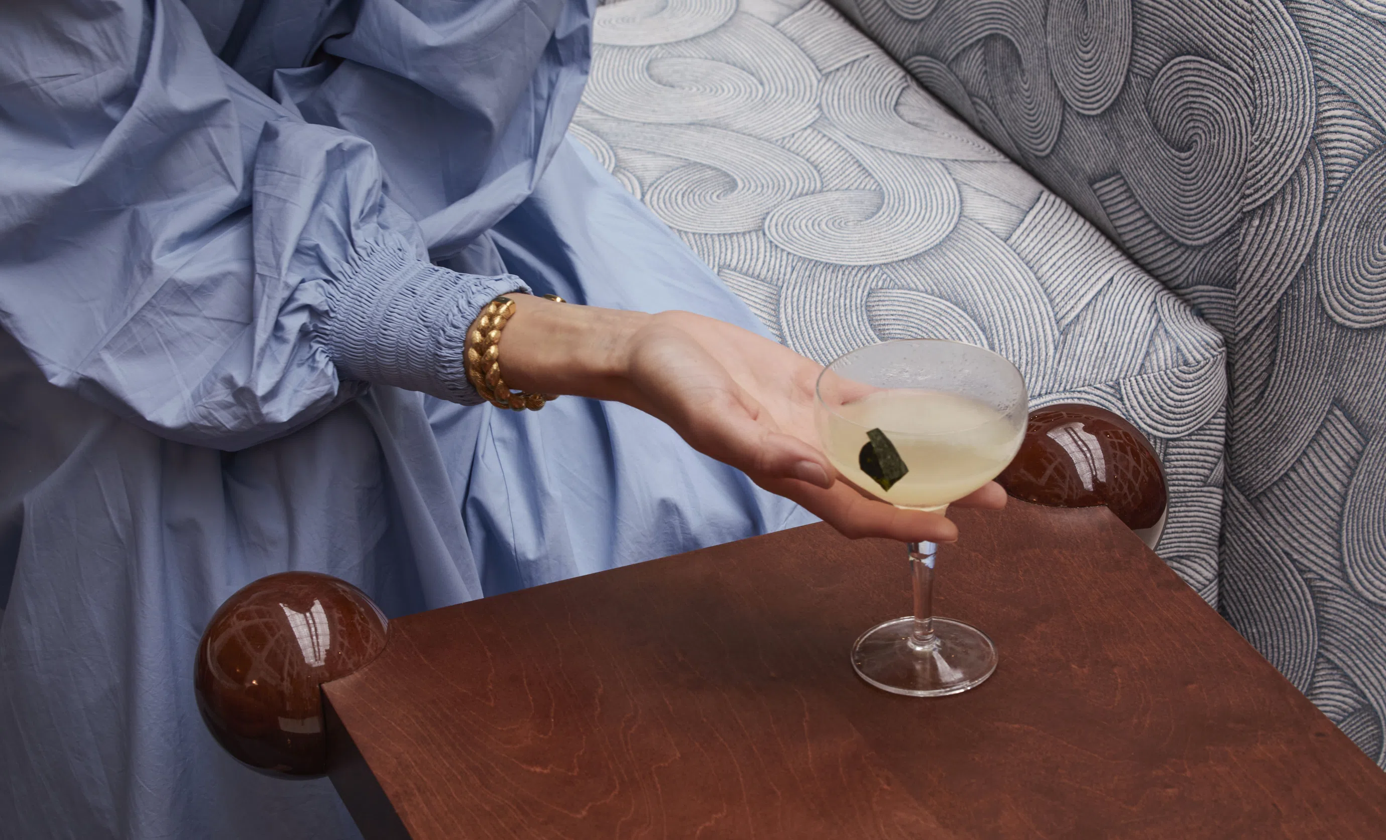 Close-up of a hand holding a craft cocktail in a sophisticated bar setting at an Experimental Group hotel.