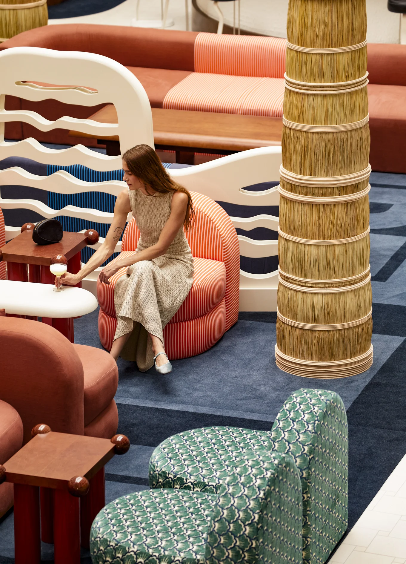 Woman sitting in the lobby lounge of Experimental Roma in Rome, holding a drink.