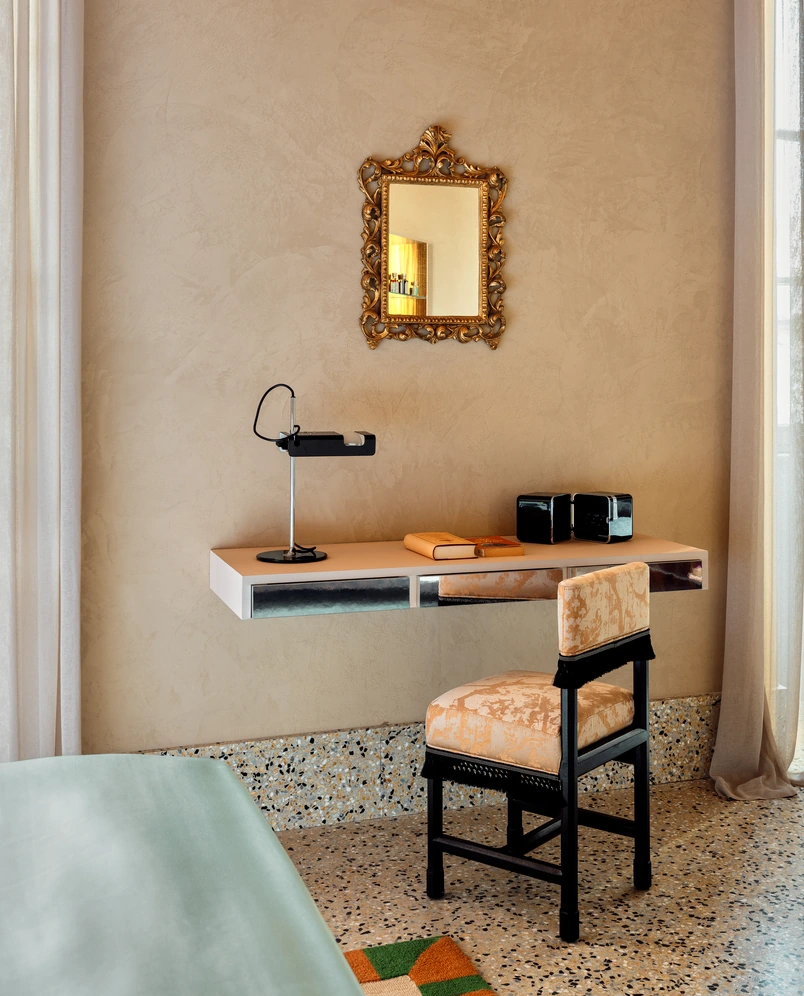 Minimalist desk with a gold mirror in a hotel room at Experimental Roma, Rome.